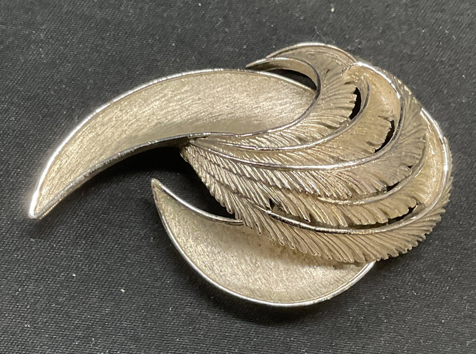 Vintage Trifari Silver Tone Swirl Brooch: Vintage Trifari brushed silver tone swirl motif brooch. Signed to underside. Hinge pin to underside. Measures approx. 2.5 x 1.5 inches. Some surface wear including scratching observed. Estate jewelry,