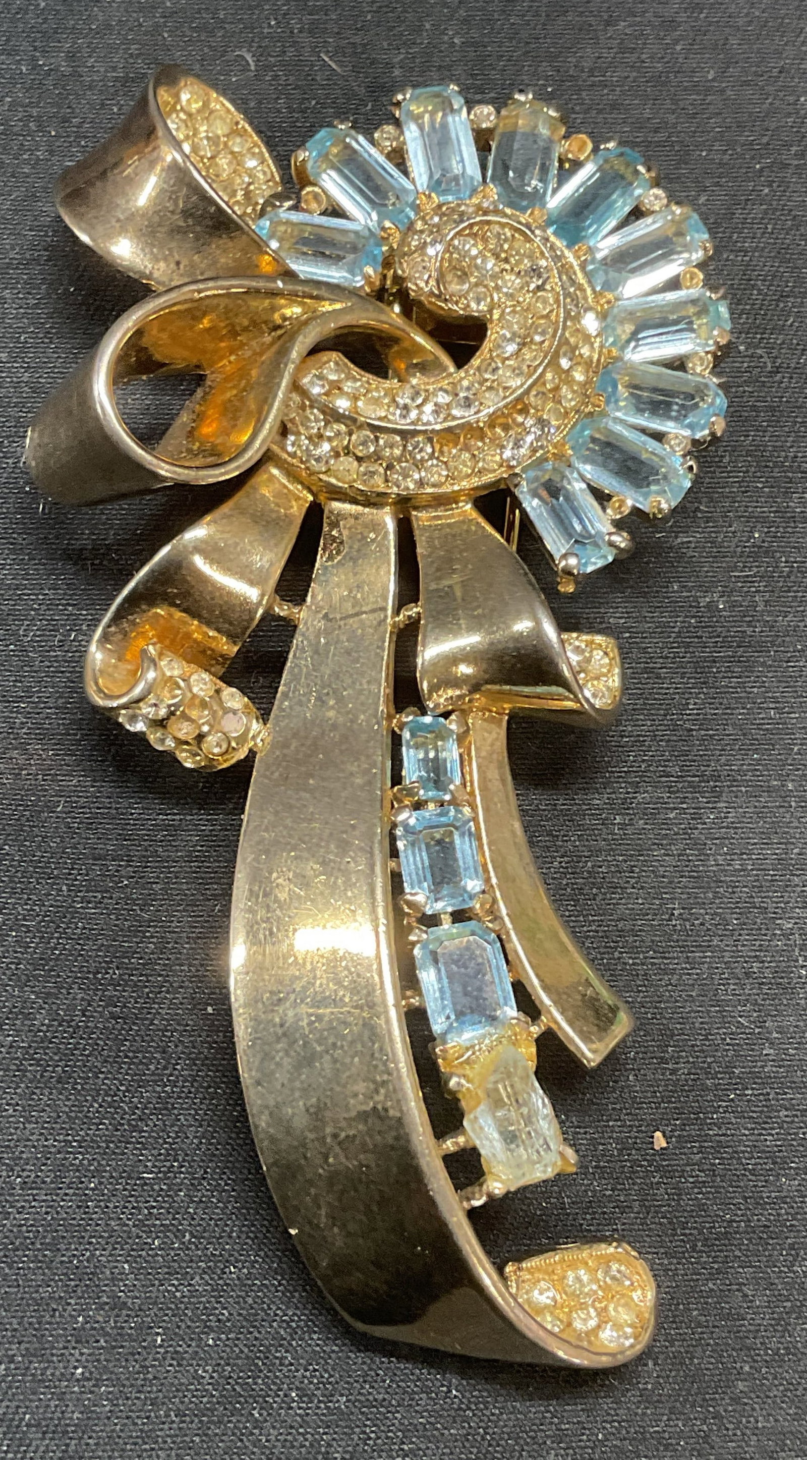 Vintage Trifari Gold Pl Sterling Silver Fur Clip: Vintage Trifari gold plate or vermeil over sterling silver fur clip. Ribbon motif with blue and colorless crystal decoration. Signed to underside. Marked sterling. Measures approx. 3.5 x 1.75 inches. 