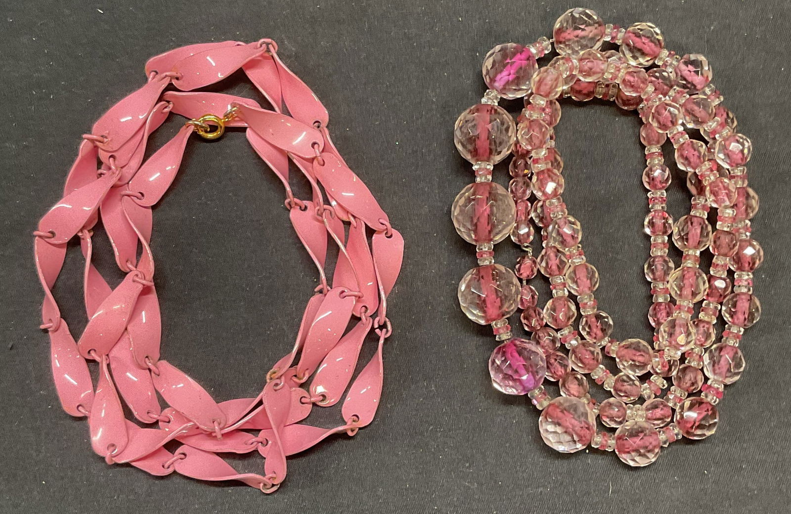 Lot 2 Crystal & Pink Enameled Necklaces: Lot of 2 jewelry pieces. Colorless crystal and pink toned beaded necklace. Drop length approx. 17 inches. Pink enameled metal necklace. Drop length approx. 20.5 inches. Some surface wear to both piece