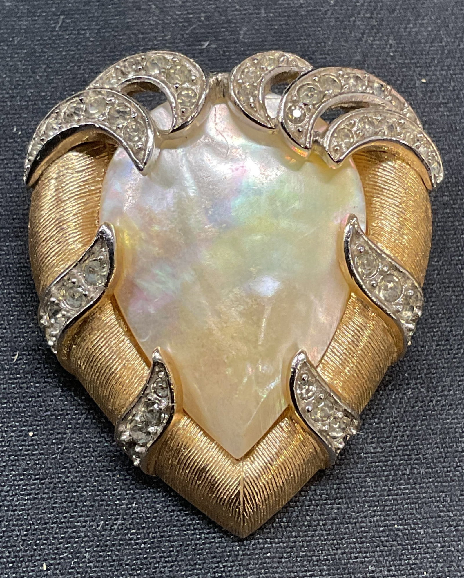 Vntg Trifari Mother of Pearl & Crystal Brooch: Vintage Trifari Fantasia series brushes gold tone brooch with mother of pearl and crystal decoration. Signed to underside. Hinge pin to underside. Measures approx. 1.25 x 1 inches. Some surface wear i