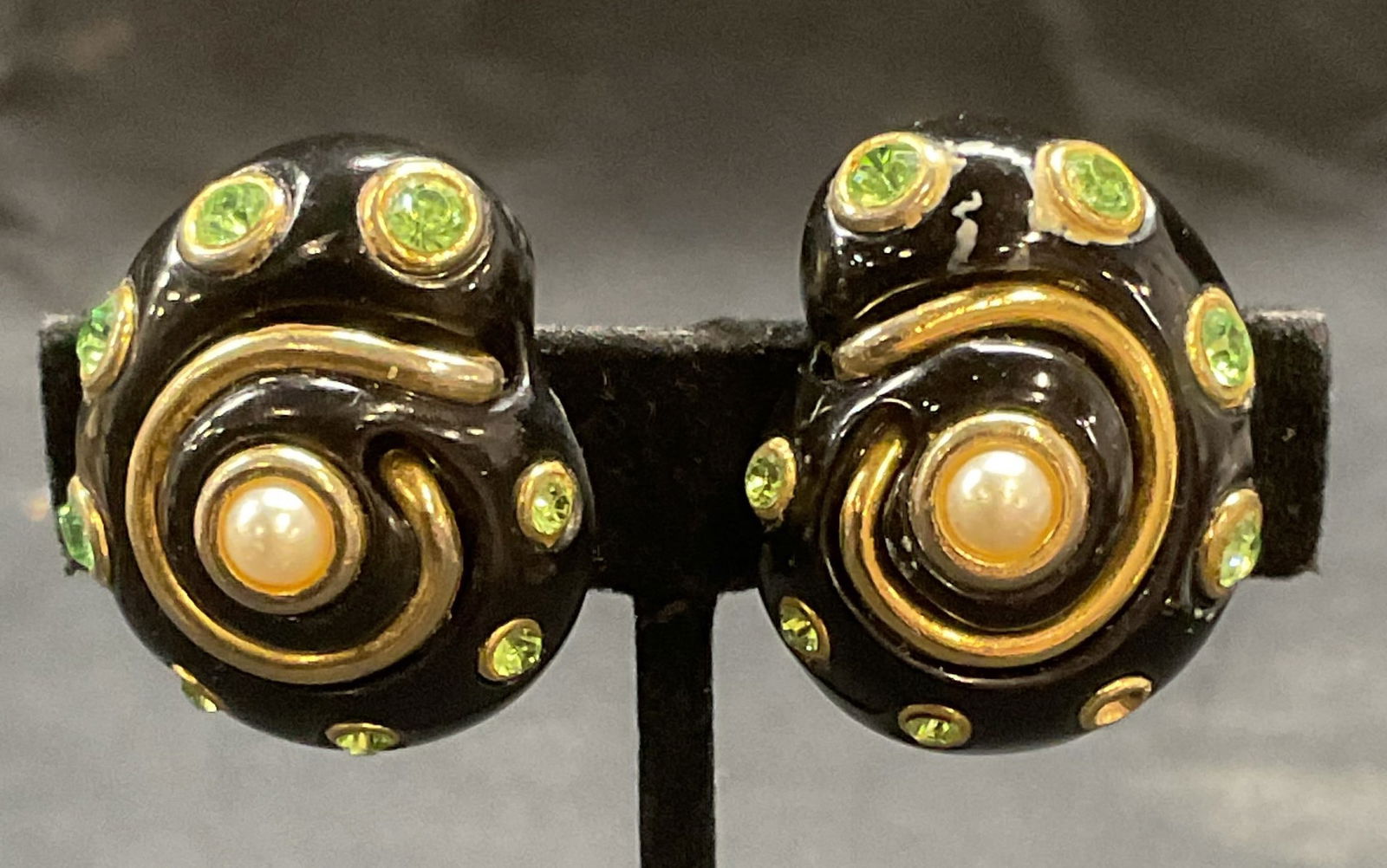 Kenneth Lane Lucite Gold Tn Crystal Shell Earrings: Vintage Kenneth Lane black lucite shell motif earrings with gold tone accents, faux pearl and green crystal decoration. Signed to underside. Measure approx. 1.25 x 1 inches. Some surface wear includin