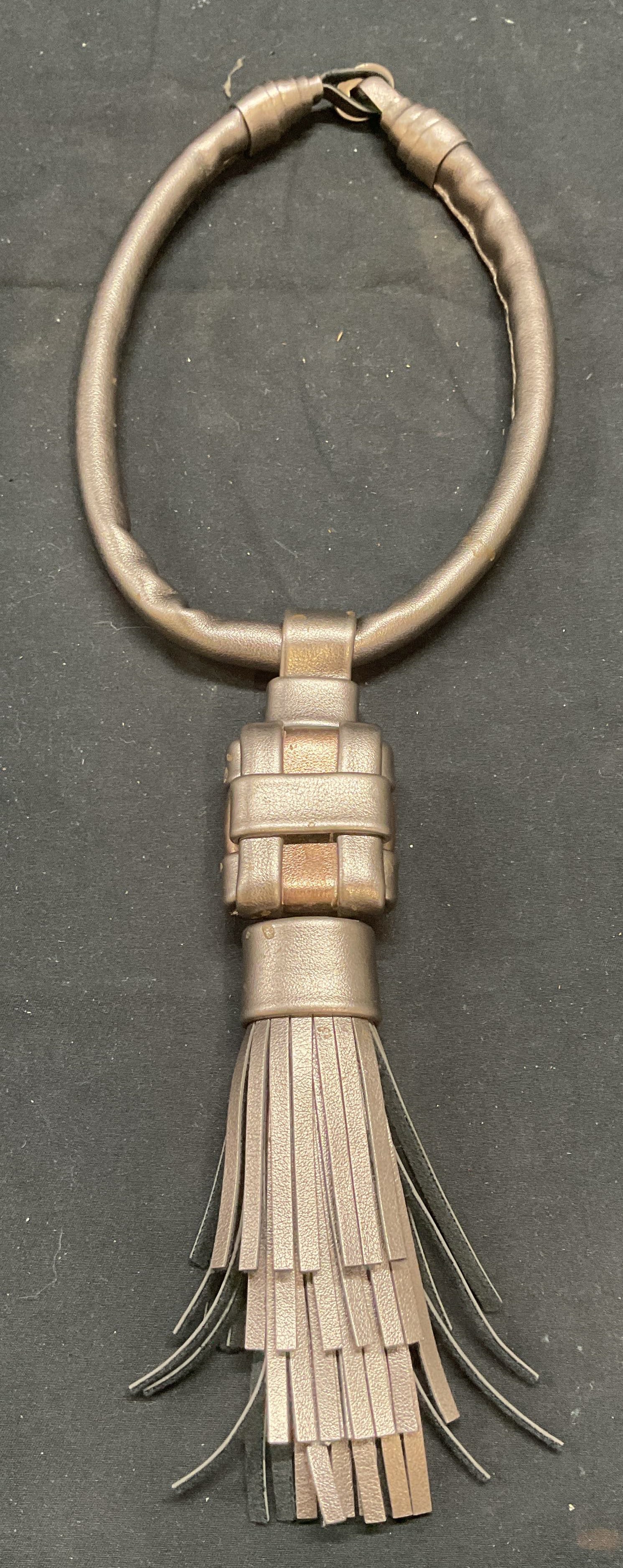 Metallic Leather Tassel Pendant Necklace: Metallic silver and bronze tone leather choker pendant necklace with tassel decoration. Drop length approx. 7 inches. Tassel measures approx. 7.5 inches long. Some surface wear including scratching ob
