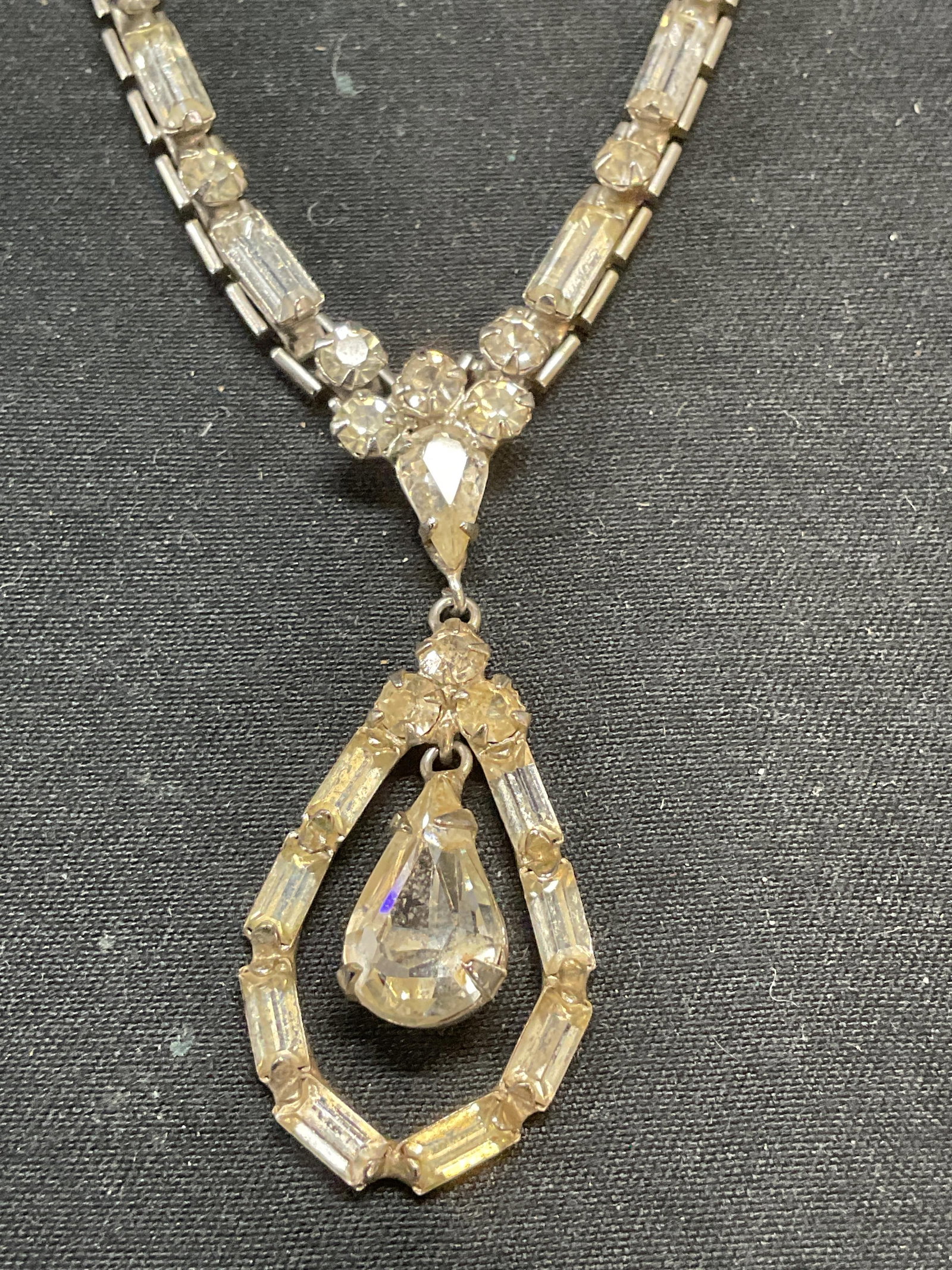 Vintage Silver Tone Crystal Pendant Necklace: Vintage silver tone pendant necklace with colorless crystal decoration. Drop length approx. 7 inches. Pendant measures approx. 1.25 inches long. Some surface wear including scratching observed. Jewelr