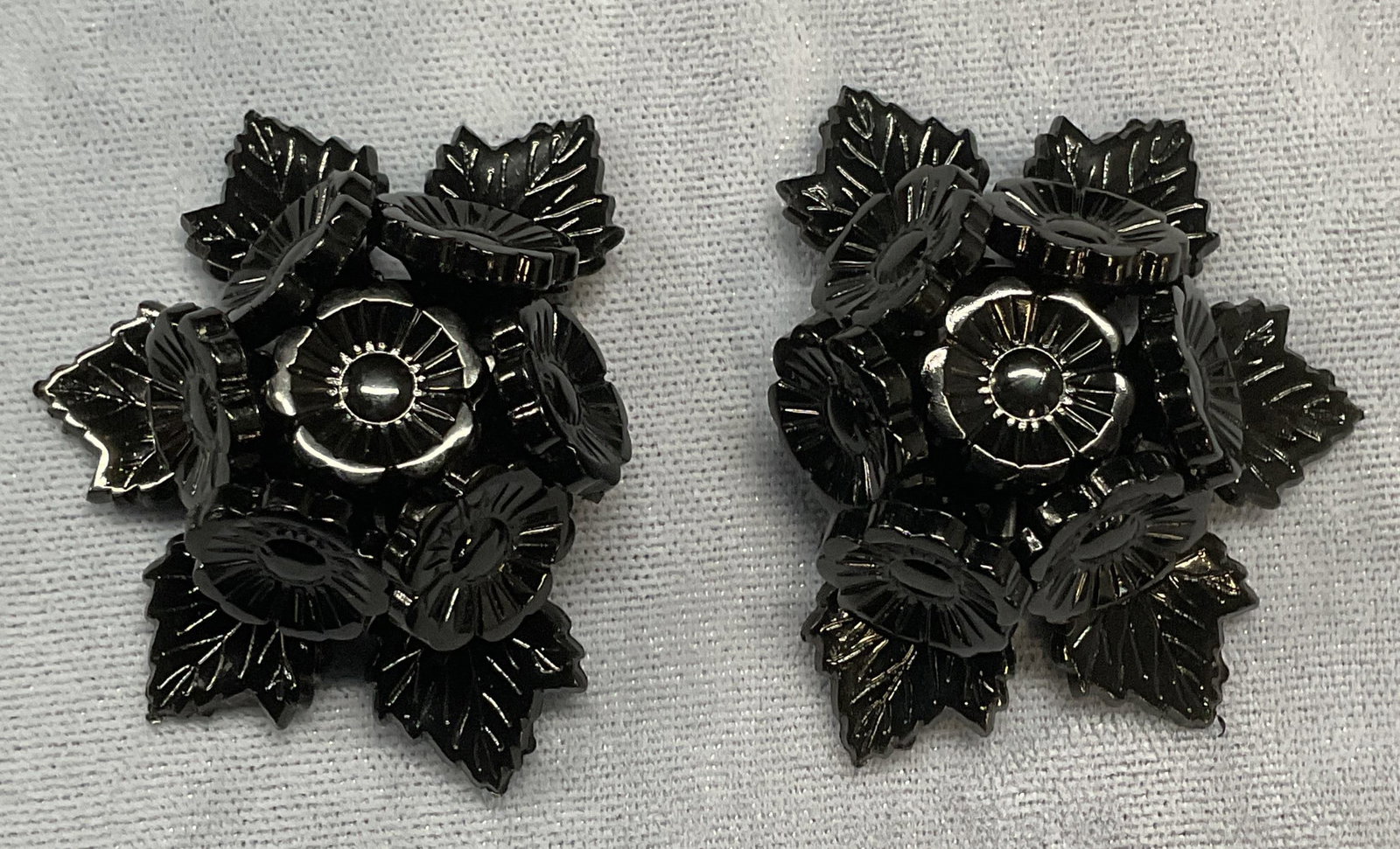Pair Black Flower Motif Sweater/Dress Clips: Pair of black flower motif sweater, dress, fur, or scarf clips. Measure approx. 1.5 x 1.75 inches each. Some surface wear including scratching observed. Jewelry, estate jewelry, costume jewelry, cockt