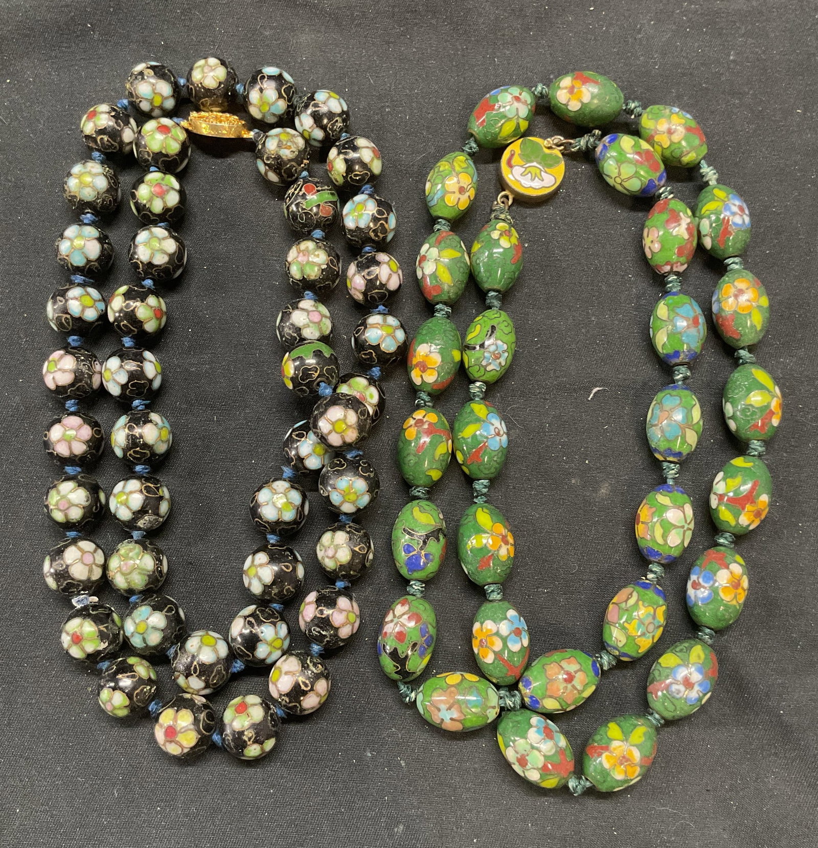 Lot 2 Vintage Black & Green Cloisonne Necklaces: Lot of 2 vintage cloisonne necklaces in black and green. Enamel over brass. Round beads on double knotted strings. Both necklaces drop length approx. 12 inches. Necklaces have weight. Some surface wea