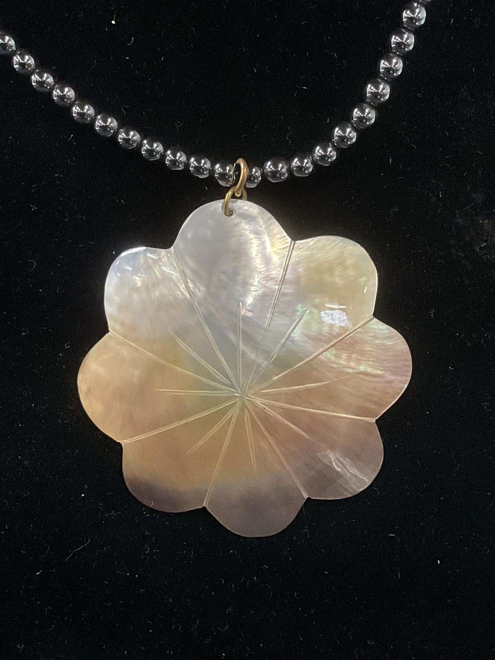 Vintage Blue Beaded Mother of Pearl Necklace: Vintage blue metallic beaded necklace with carved mother of pearl flower pendant. Drop length approx. 7.5 inches. Pendant measures approx. 2 inches wide. Some surface wear including scratching observe