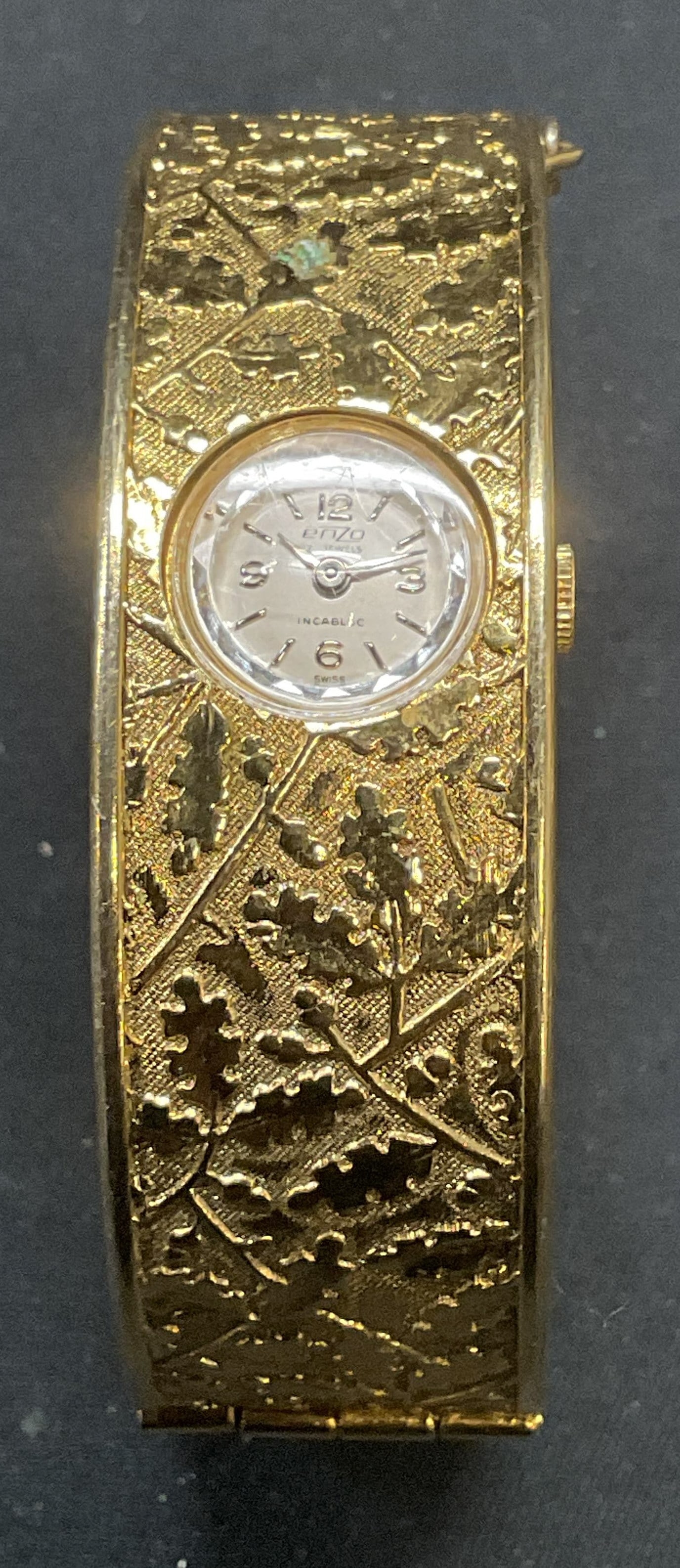 Enzo Incabloc Gold Tone Bracelet Watch: Enzo incabloc Swiss made bracelet watch. Signed on dial. Hinged bangle with raised botanical scroll pattern. Measures approx. 2.25 inches wide. Not tested for function. Some surface wear including scr