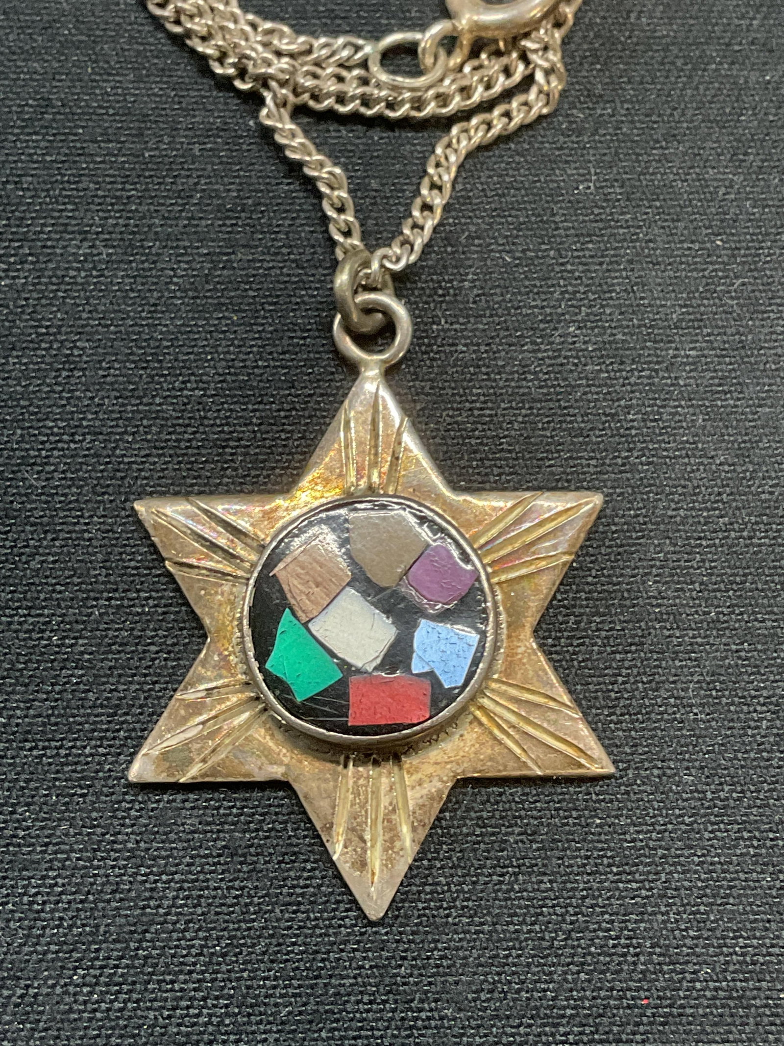 Sterling Silver Star of David Pendant Necklace: Sterling silver chain necklace with sterling silver Star of David pendant. Multicolor glass inlay on pendant. Marked 925 on clasp and pendant. Drop length approx. 9.75 inches. Pendant measures approx.