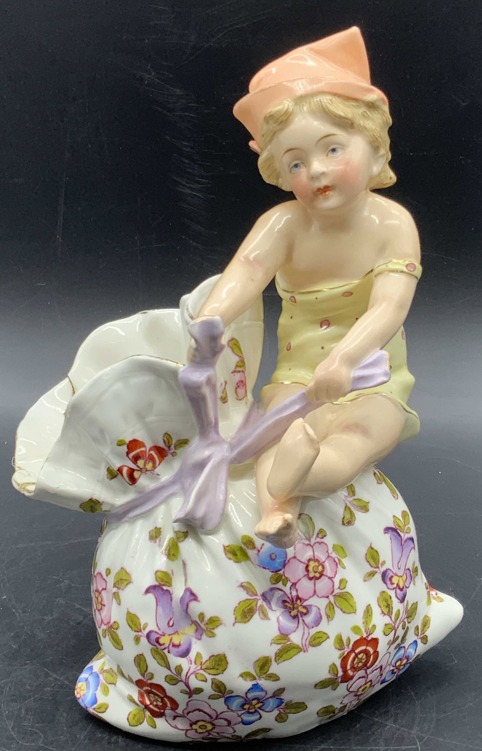 Schutz Marke Signed Girl Atop Floral Bag Figural: Schutz Marke Signed Girl Atop a Fancy Pansy Flower Bag Figural Vase. She wears a polka dot dress. Underside is signed. Measures approx. 8H x 4W in. Repair present. Cracking, chipping, discoloration pr