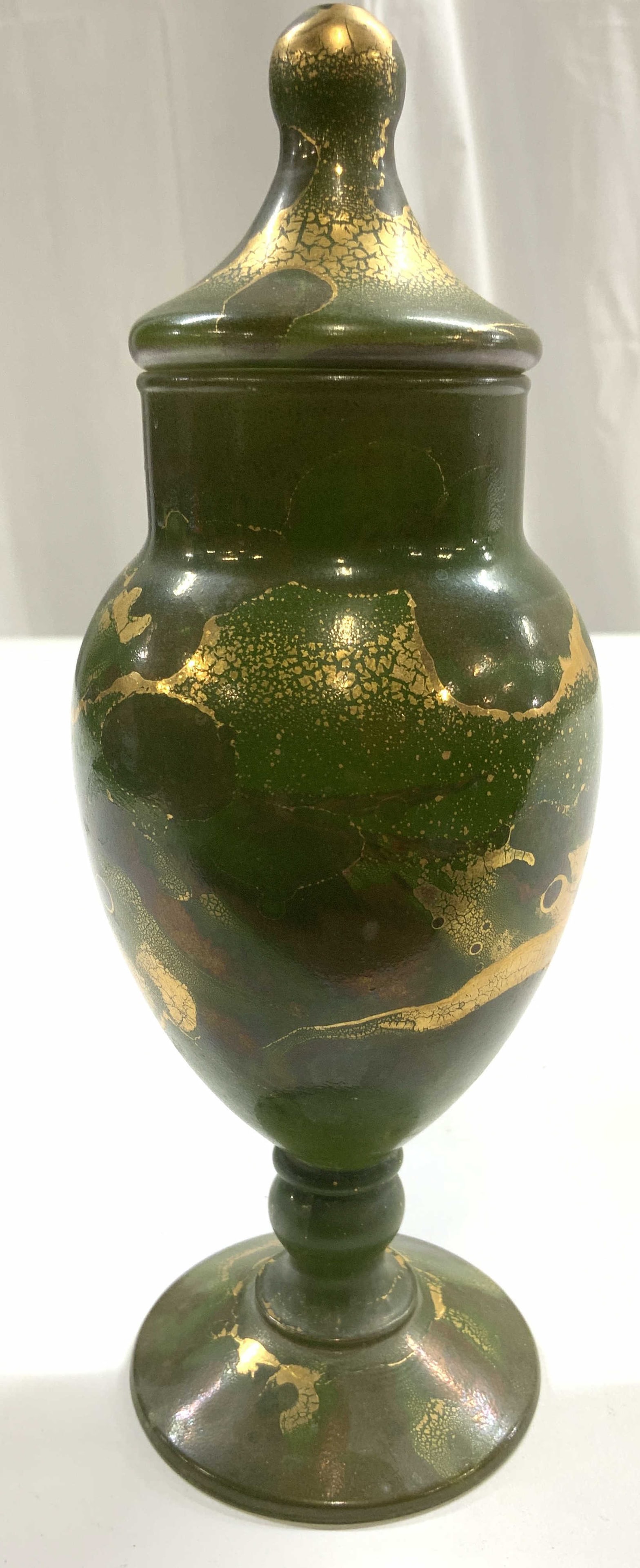 Art Glass Vessel W Lid & Gilt Detail Green: Vessel is green toned with gilt detail. Piece includes lid & base has stem. Vessel has urn form. Piece measures approximately 8 inches tall 3 inches wide. Vessel, art glass, art glass vessel, vessel w