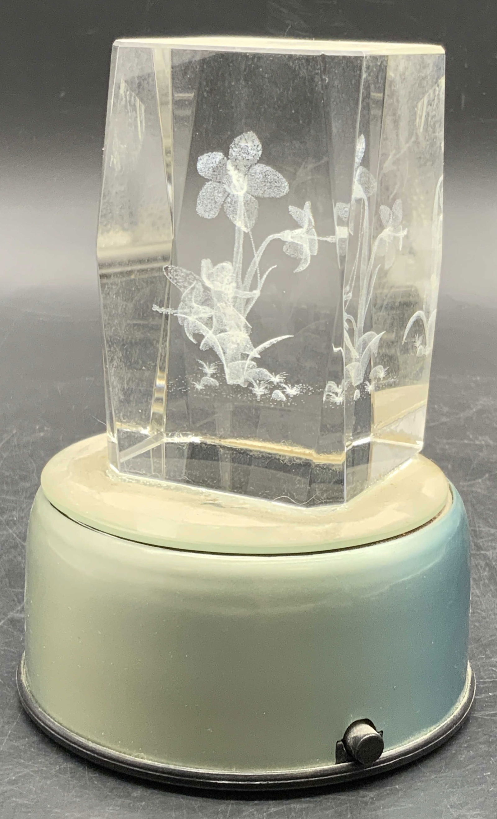 Bubblegram Fairy Floral Glass Paperweight W/ Base: A bubblegram glass paperweight featuring a fairy swinging amongst florals. The paperweight is affixed to a base. Together the pieces measure approx. 5H x 3.5W in. The base is not tested for function.