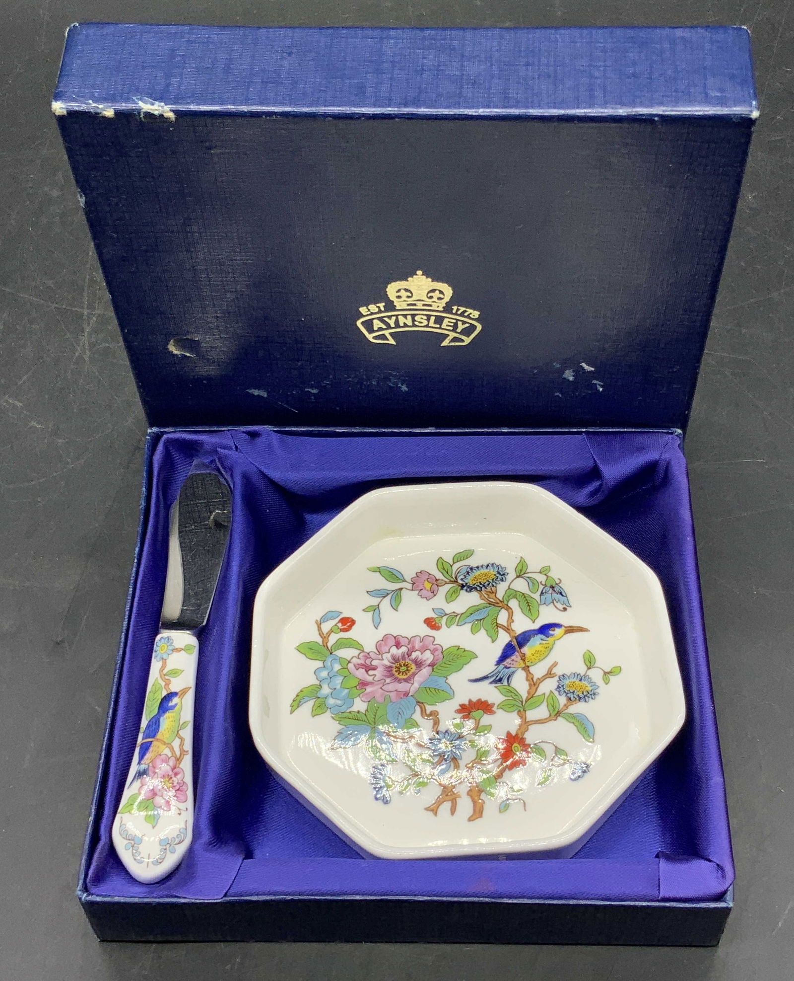 AYNSLEY NIB Butter Dish & Butterknife, England: NIB Bone China Butter Dish and Butterknife Set by Aynsley, England. Underside of butter dish is signed. Pieces are contained in a royal blue hued box, lidded interior. The box measures approx. 1H x 6W
