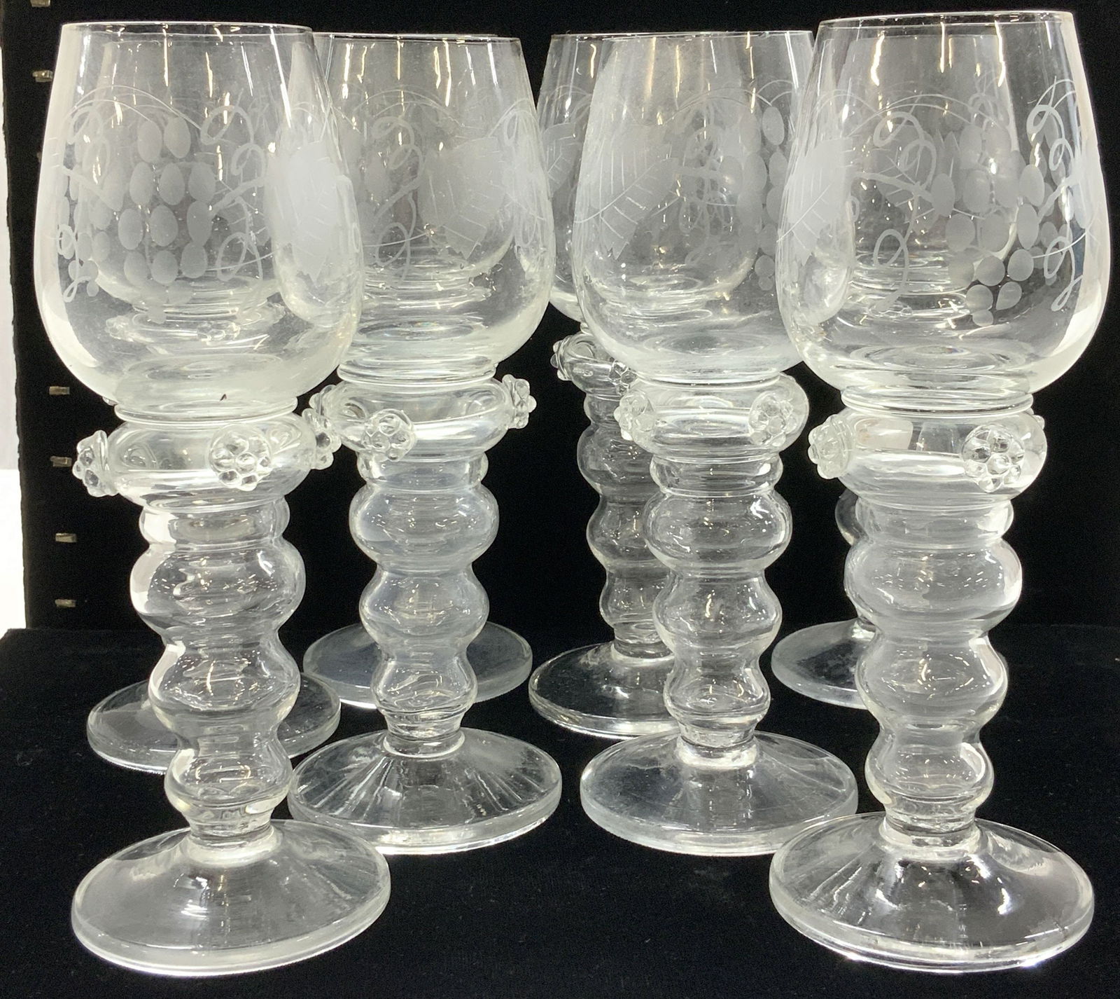 Set 8 Blown & Etched Glass Wine Goblets: Hand blown Wine goblets with etched motif of grape bunch and grape vines. Raised flower detail at top of the bulbous stem. Pontil mark on underside. Glasses measure 8 in Ht x 3 in. Wide . One glass ha