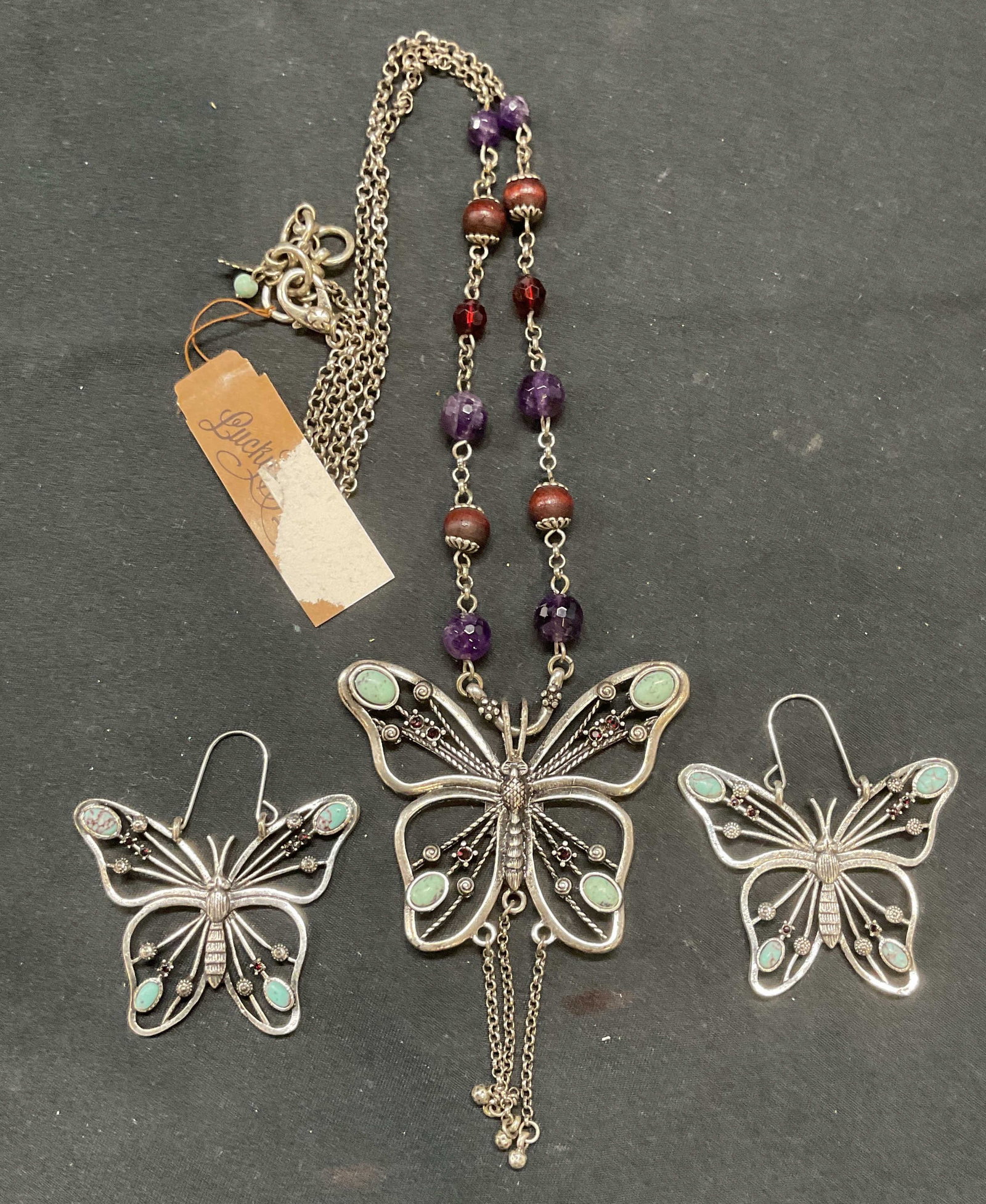 2 Lucky Brand Butterfly Semi Precious Necklace +: Lot of 2 jewelry pieces. Lucky Brand silver tone butterfly motif pendant necklace and matching earrings with semi precious stone accents. Necklace drop length approx. 12 inches. Earrings measure appro