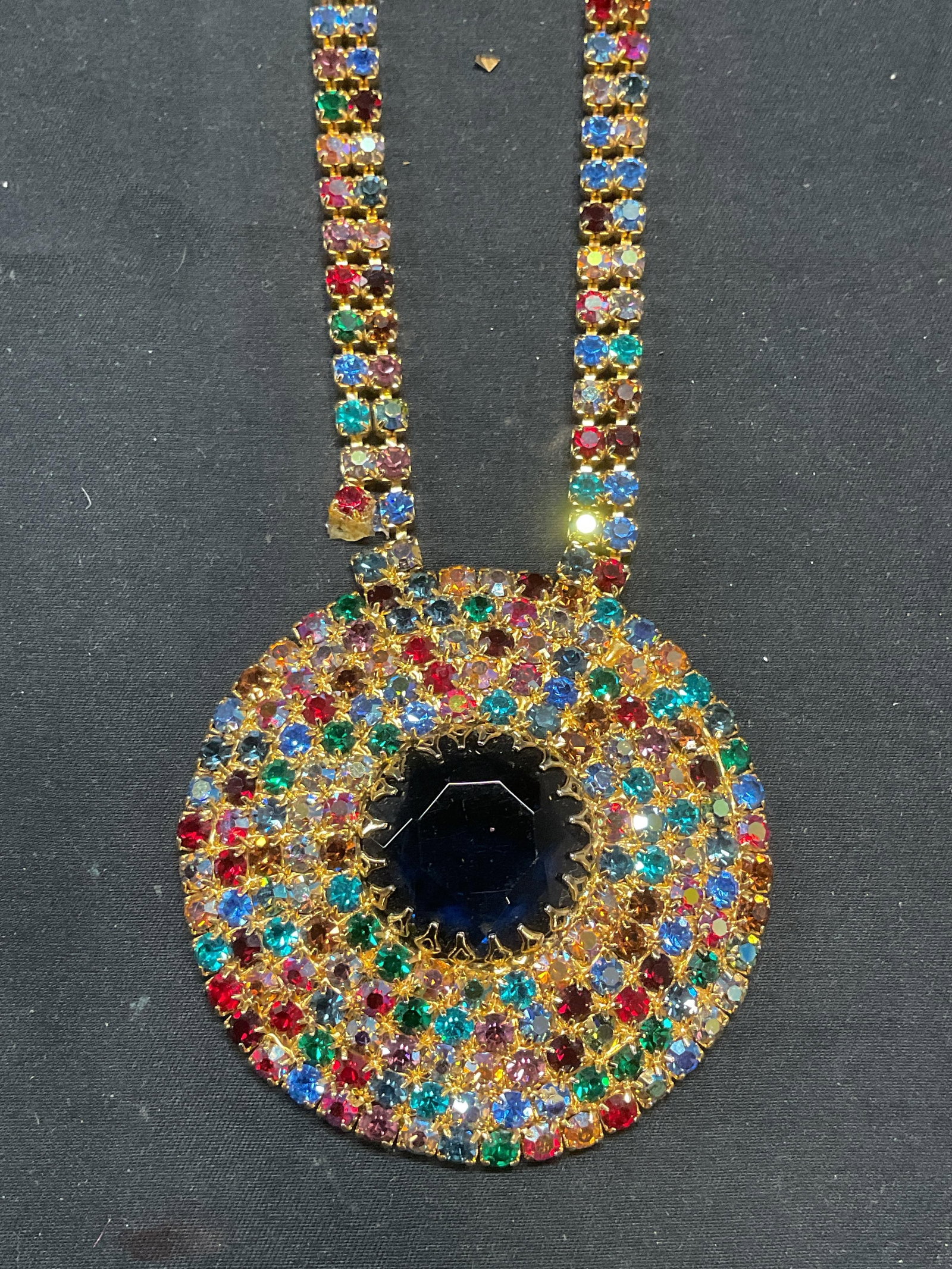 Gold Tn Multicolor Crystal Pendant Necklace: Gold tone pendant necklace with multicolor crystal decoration. Drop length approx. 15 inches. Pendant measures approx. 2.5 inches diameter. Necklace has weight. One piece needs repair. Some surface we