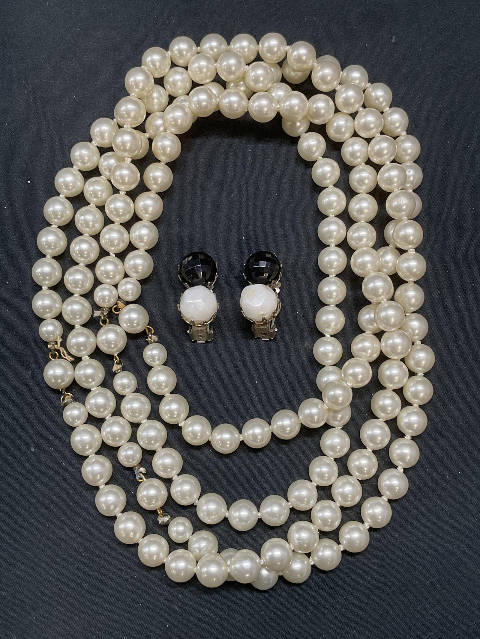 Lot 2 Faux Pearl Necklace & Crystal Earrings: Lot of 2 jewelry pieces. Faux pearl beaded necklace on double knotted string. Drop length approx. 30.5 inches. Faux pearl and black crystal clip on earrings. Measure approx. 1 inch long. Some surface