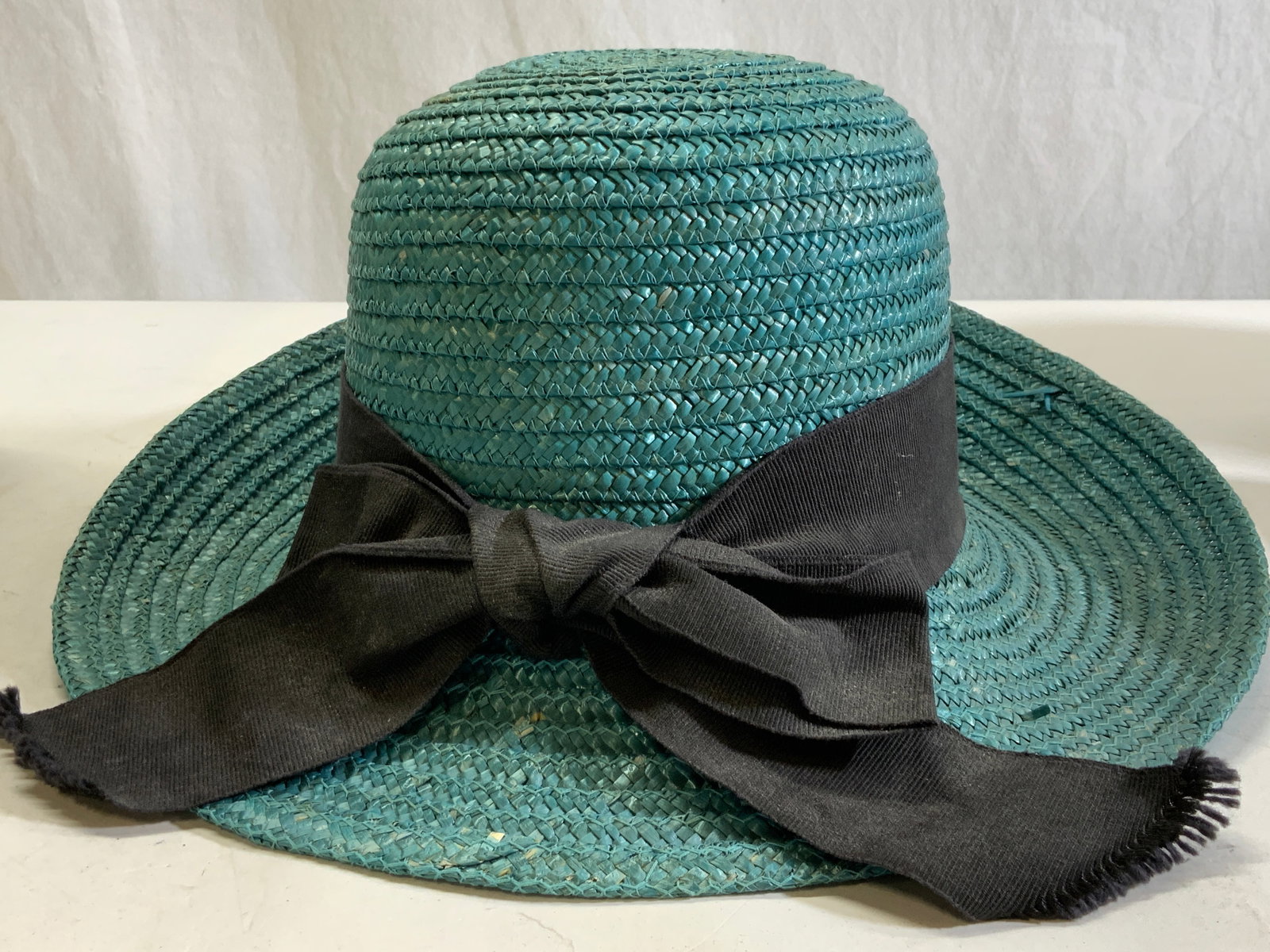 Saks Fifth Ave Aqua Straw Hat, Italy: Vintage, labels read 100% straw. hat in a dark aqua. Label reads Saks Fifth Avenue made in Italy. Black ribbed bow, part of brim rolled upward. head circumference measures 21.5. Light discoloration on