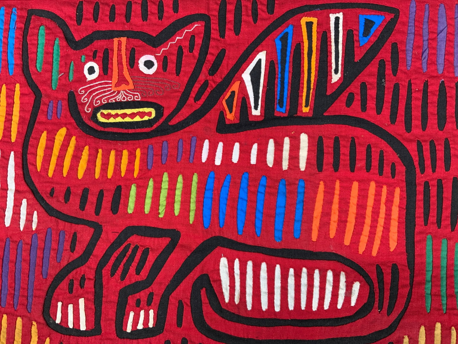 Traditional Columbia Panama Mola Textile Art: Traditional mola from Columbia or Panama. Different colorful motifs are made with layers of different fabrics and embroidery styles. This mola depicts a winged cat with curled whiskers and sharp teeth