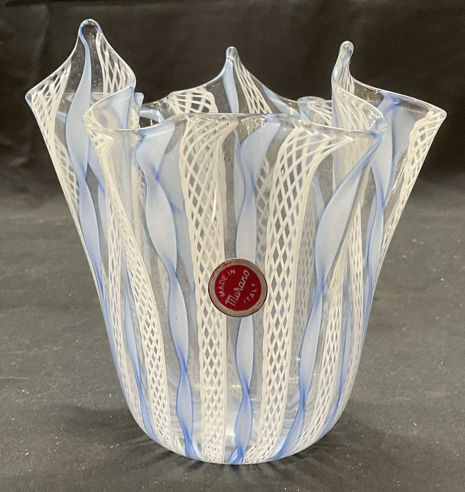 MURANO Blue & White Latticino Art Glass Vase Italy: MURANO Art glass vase. Latticino pattern in white and blue. Handkerchief rim. Signed on sticker. Made in Italy. Measures approx. 5 x 5 inches. Some surface wear including scratching observed. MURANO, 