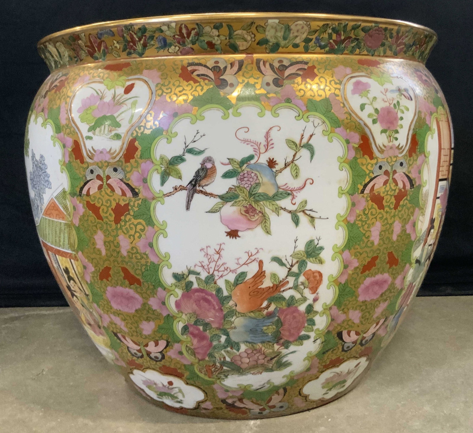 Vintage Signed Asian Porcelain Fishbowl Planter: A vintage hand painted Asian porcelain fishbowl planter. Multicolored hues with gilt accents throughout. Florals, birds, fish, foliage, and people wearing traditional clothing throughout the design. T