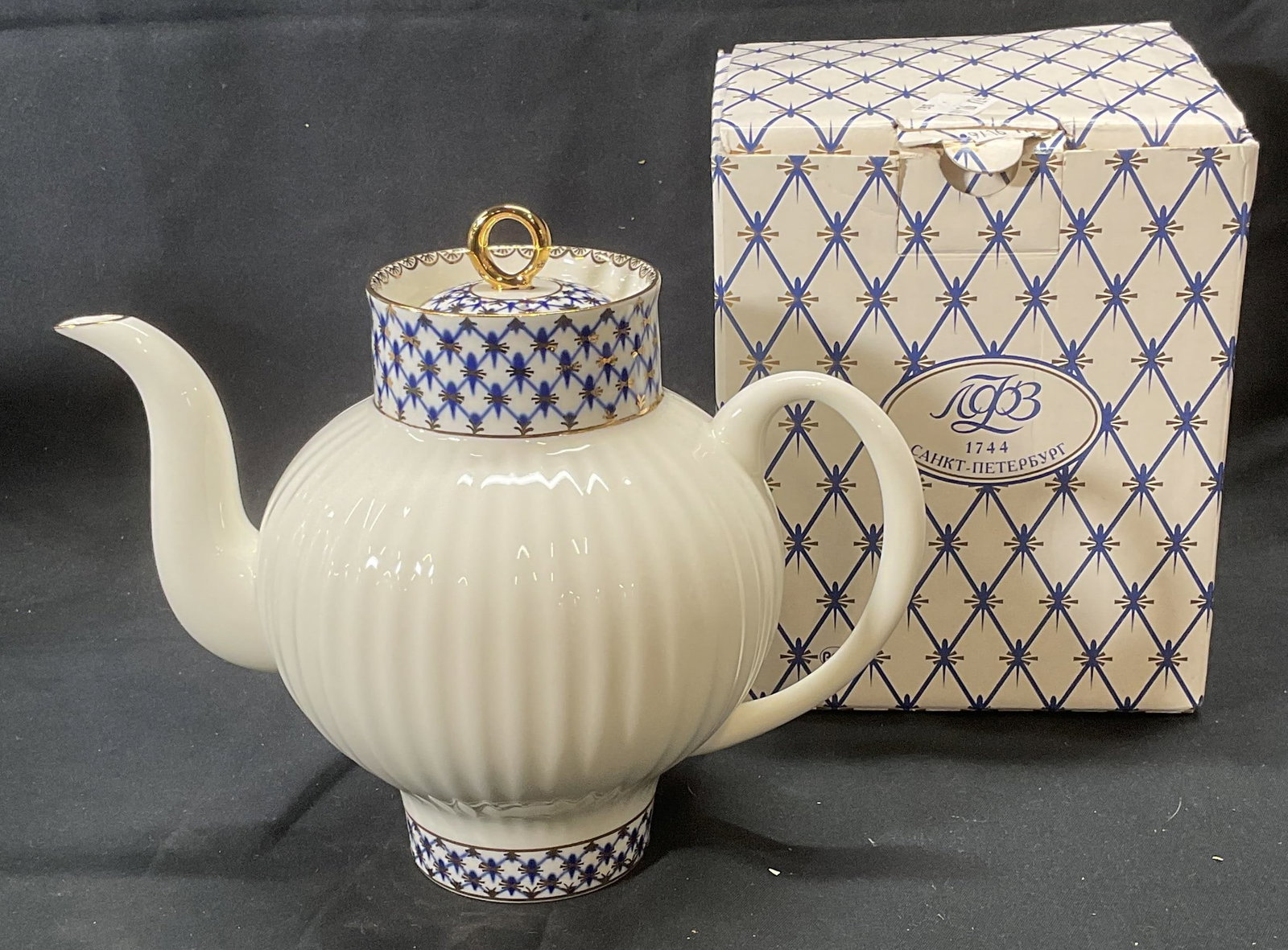 LOMONOSOV Gilt Porcelain Teapot, Russia: LOMONOSOV white porcelain teapot with hand painted trim in blue and gilt border decoration. Trademarked to underside. Made in Russia. Includes box. Teapot measures approx. 7.75 x 6 inches. In good con