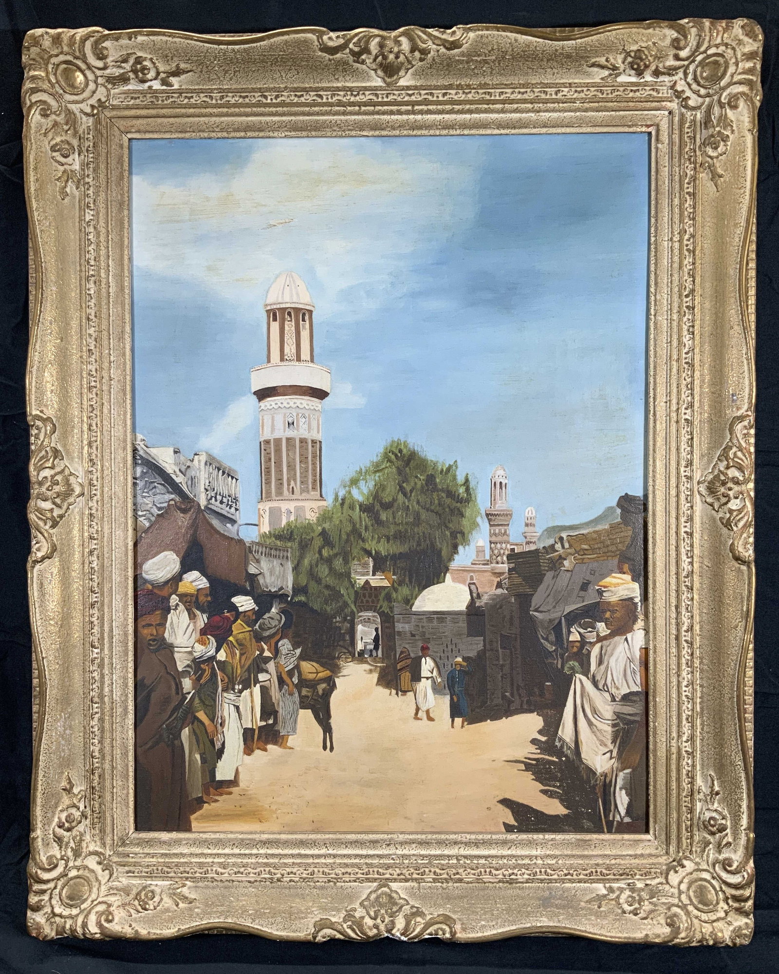 Sanaa, Yemen in the Fifties Acrylic Painting: Acrylic painting on canvas board. Subject depicts Sanaa in the 1950s, a road with men walking around. Painting based on a photograph. Framed in gilt wooden frame with scrolling and foliage molding. Fr
