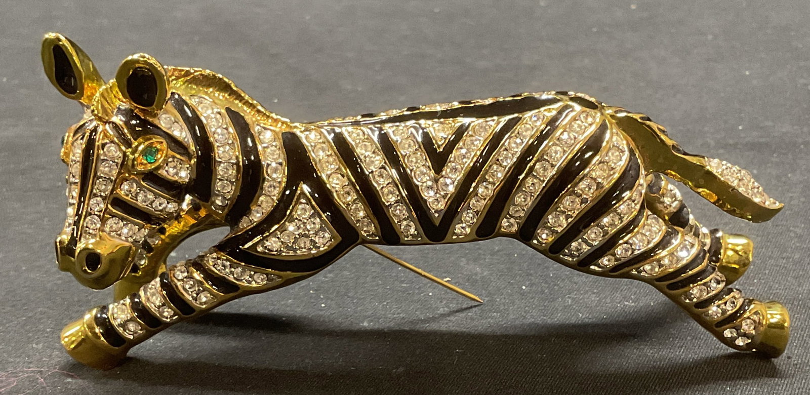 XL Vintage Crystal Zebra Shoulder Brooch 4.5In: Vintage gold tone zebra figural shoulder brooch. Black enamel, green and colorless crystal decoration. Unsigned, style of Joanna Buchanan. Measures approx. 4.5 x 1.5 x 2 inches. Hinge pin to underside