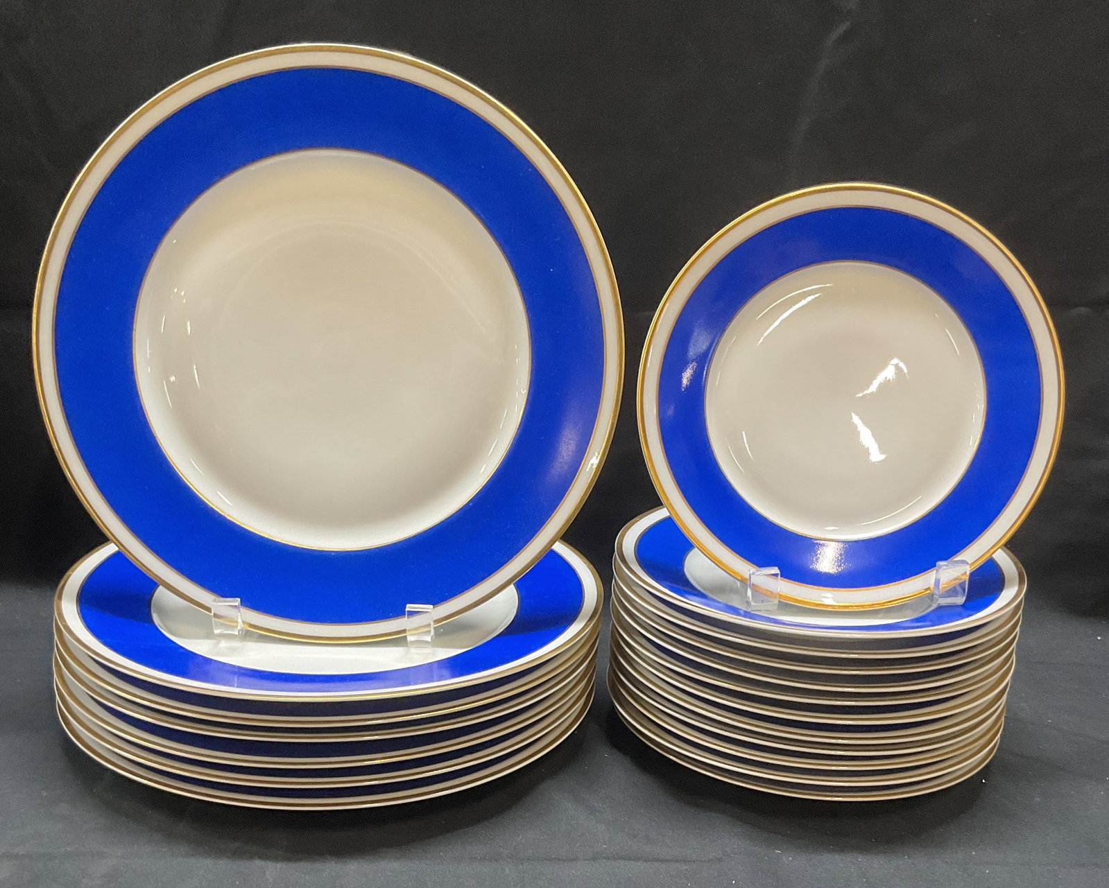 21 Royal Limoges for Bloomingdales Porc Plates: Set of 21 Ancienne manufactured Royale Limoges porcelain plates made for Bloomingdales. White with cobalt blue border and gilt trim. Hand painted. Signed to undersides. Made in France. Includes 7 dinn
