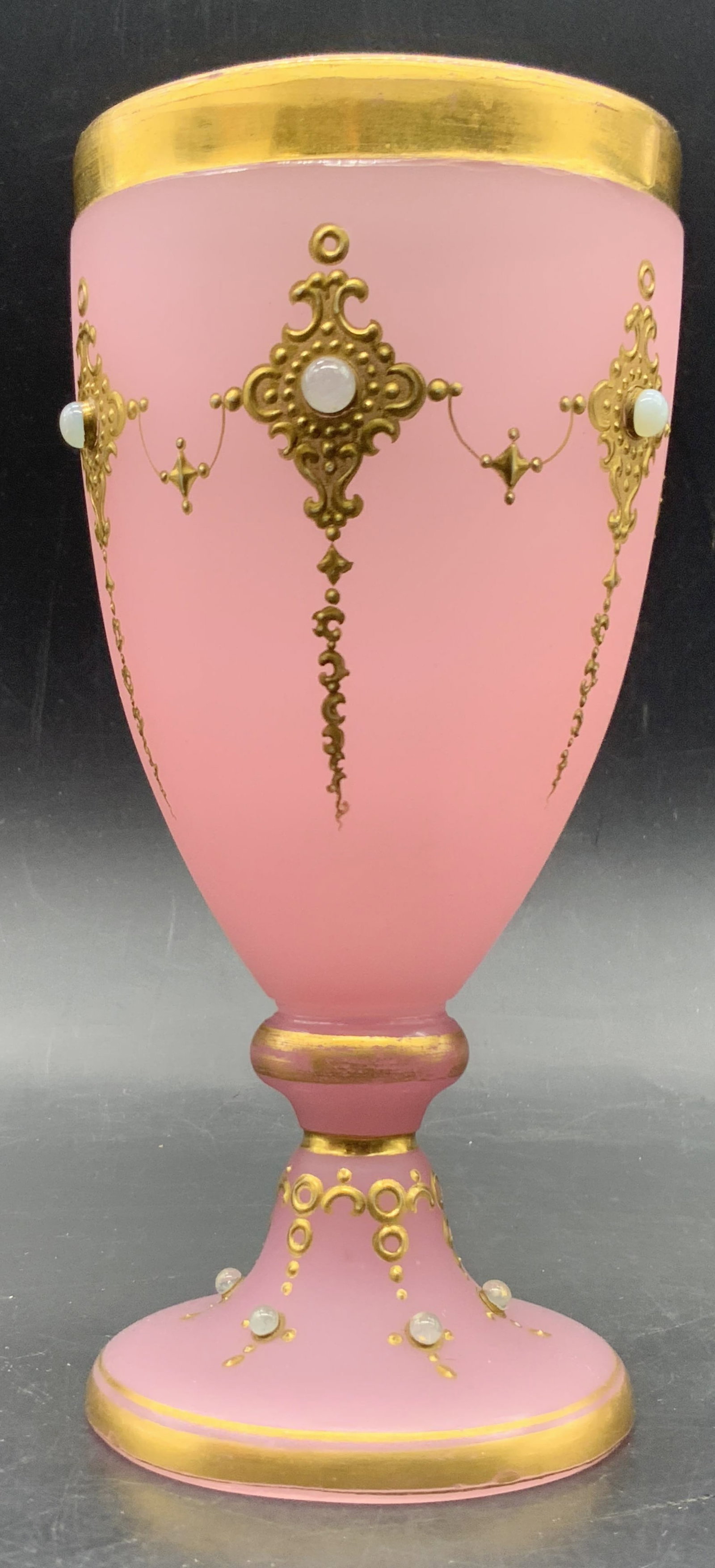 Pink Art Glass Bejeweled Gilt Chalice: A pink art glass chalice with raised circular costume cabochons and gilt accents. Measures approx. 6H x 3W in. Some losses to the gilt and missing cabochons. Surface wear consistent with age, use, and