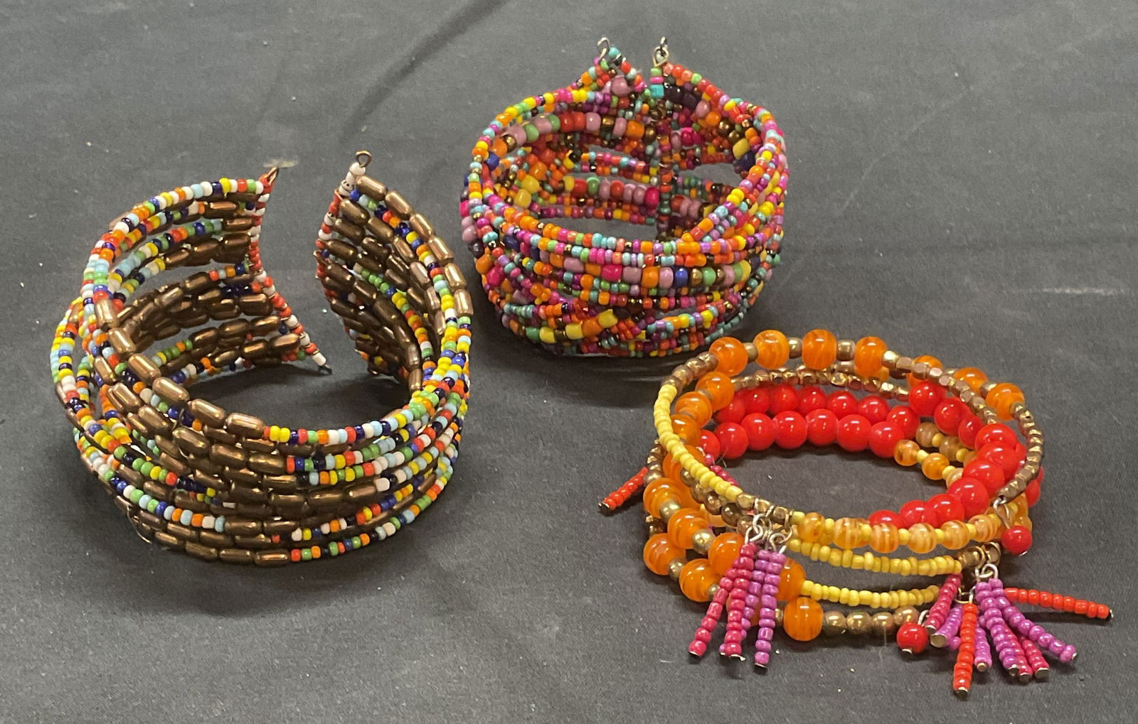 Lot 3 Multicolor Seed Bead Bracelets: Lot of 3 multicolor seed beaded wrap and cuff bracelets. Adjustable sizes. Largest approx. 2.5 inches wide. Some surface wear to all pieces including scratching observed. Jewelry, estate jewelry, cost
