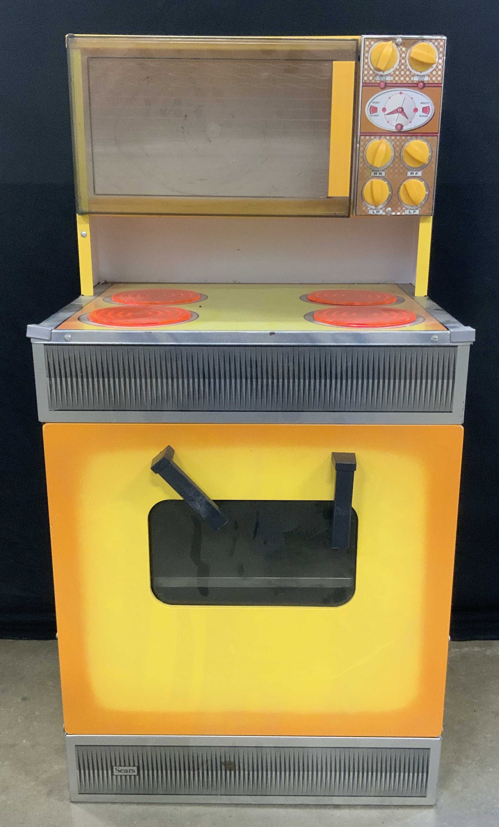 SEARS Vintage Metal Toy Range, 3ft ht: A vintage Sears toy range. Crafted from metal and composite material. Yellow exterior. Reads SEARS towards base of the exterior. Oven door and microwave door open to reveal storage space. Sticker resi