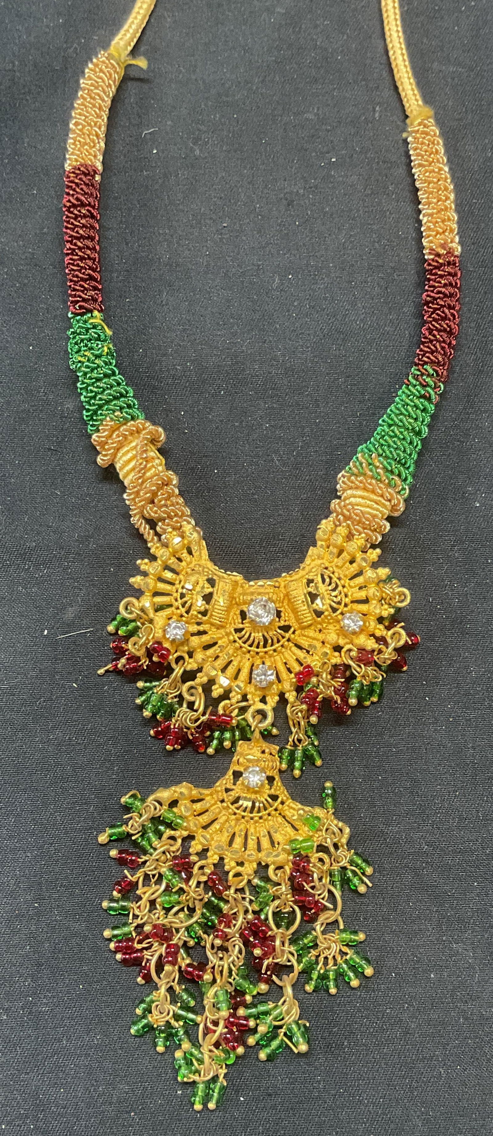 Gold Tone Crystal Beaded Pendant Necklace: Gold tone pendant necklace on string with colorless crystal and blue and green seed bead decoration. Drop length approx. 10.5 inches. Pendant measures approx. 3.5 inches long. Some surface wear includ