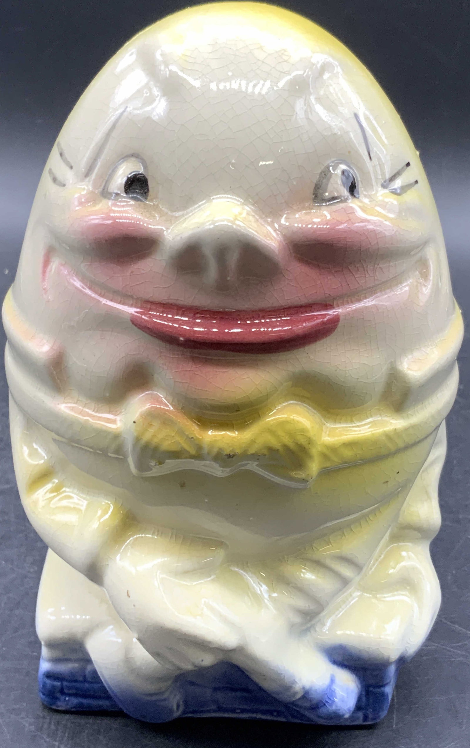 Vntg Alice in Philcoland Humpty Dumpty Figural Bank: A vintage Alice in Philcoland Humpty Dumpty Figural Glazed Ceramic Bank. Reverse reads Alice in Philcoland. Drilled holes to underside. Measures approx. 6H x 3.5W in. Crazing and pitting throughout. S