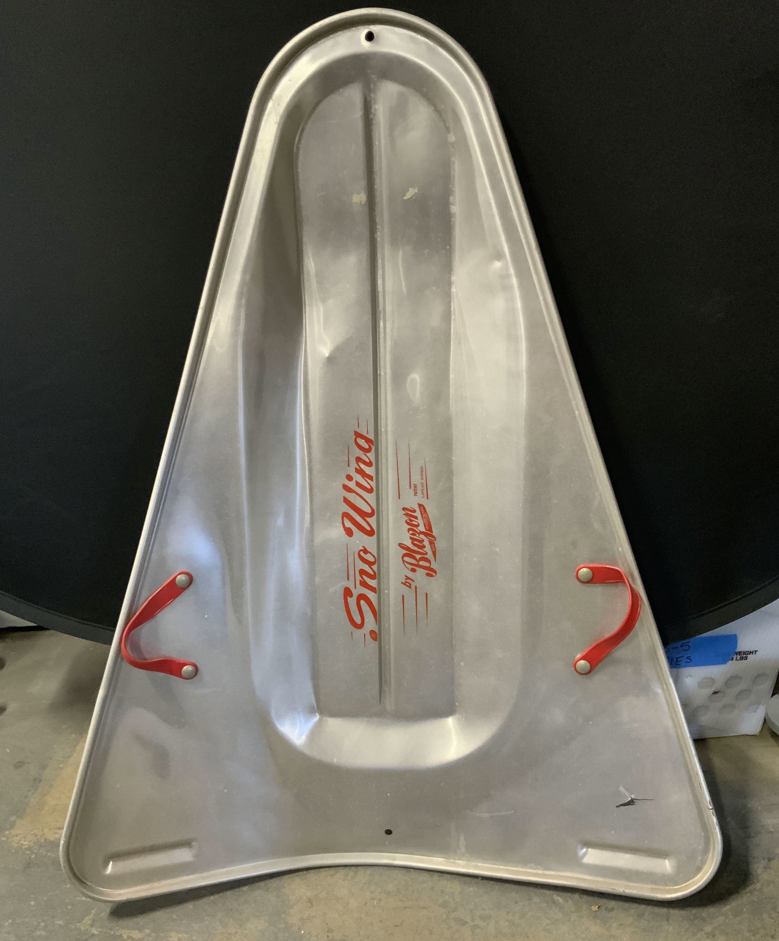 BLAZON SNO WING Vintage Red & Silver Metal Sled: A vintage red and silver metal sled. Obverse reads SNO WING, BLAZON. Red plastic handles. Measures approx. 37.5L x 28.5W in. Discoloration, residue, and surface wear present. Vintage sled, metalware, 