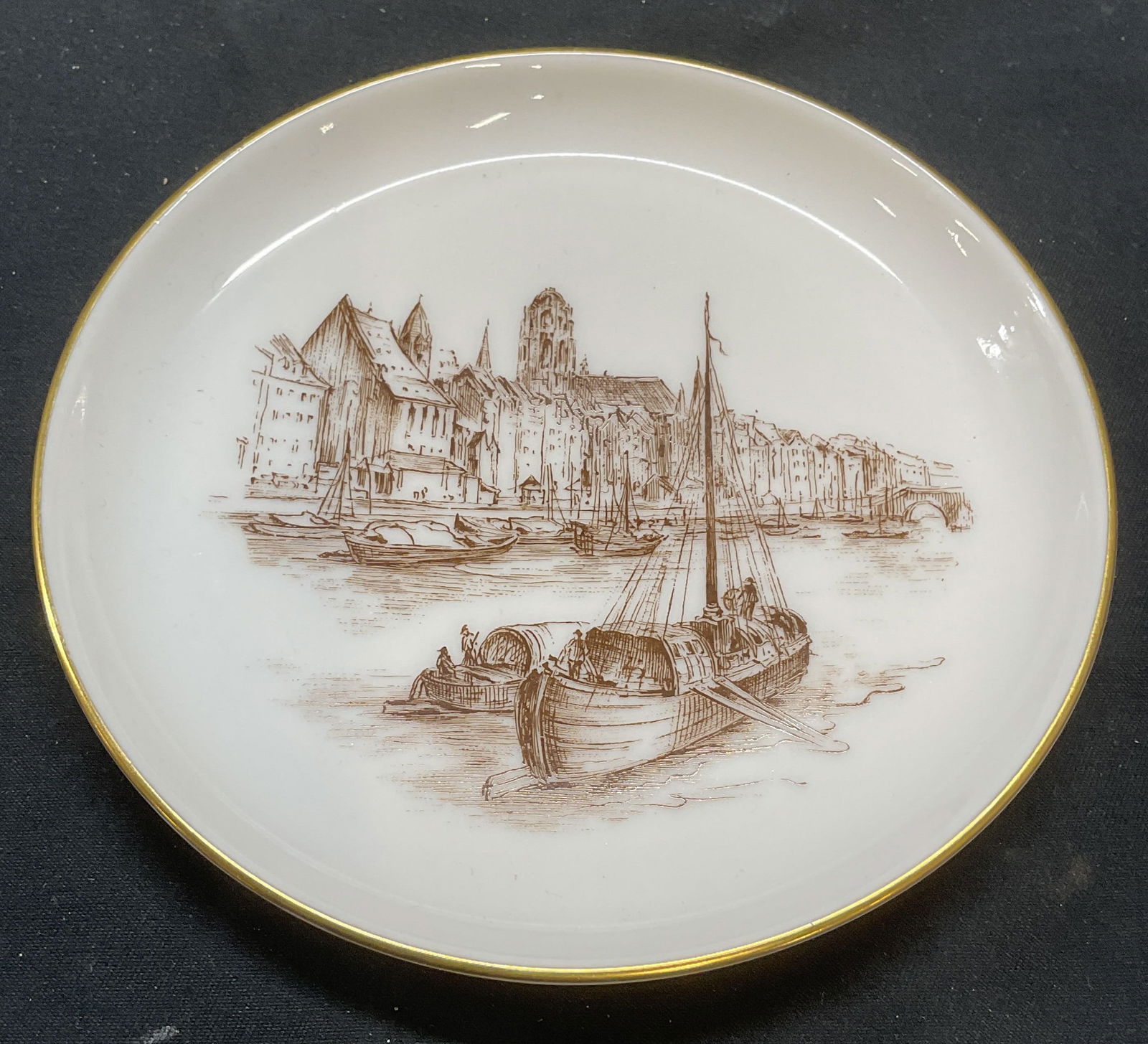 Rosenthal Messer Porcelain Plate, Germany: Rosenthal Messer porcelain plate. Boat and town motif. Gilt rim. Trademarked to underside. Made in Germany. Measure approx. 4.5 inches wide. Some surface wear consistent with exposure.