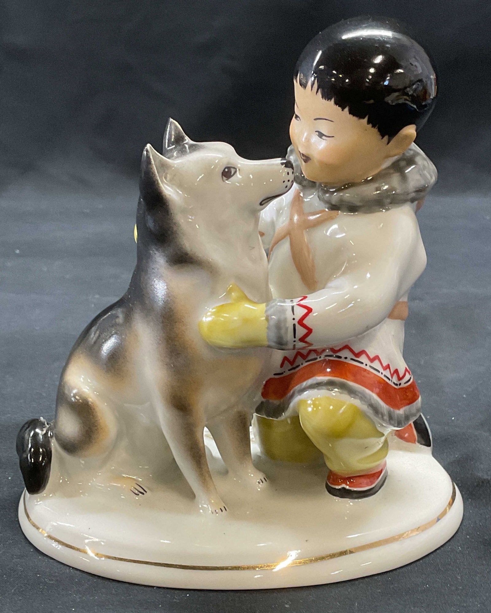 LOMONOSOV Porc Yakut Boy & Dog Figural, Russia: LOMONOSOV porcelain figural. Yakut boy and husky dog motif. Trademarked to underside. Made in Russia. Measures approx. 4.75 x 3 x 5.25 inches. Some surface wear including scratching observed. LOMONOSO