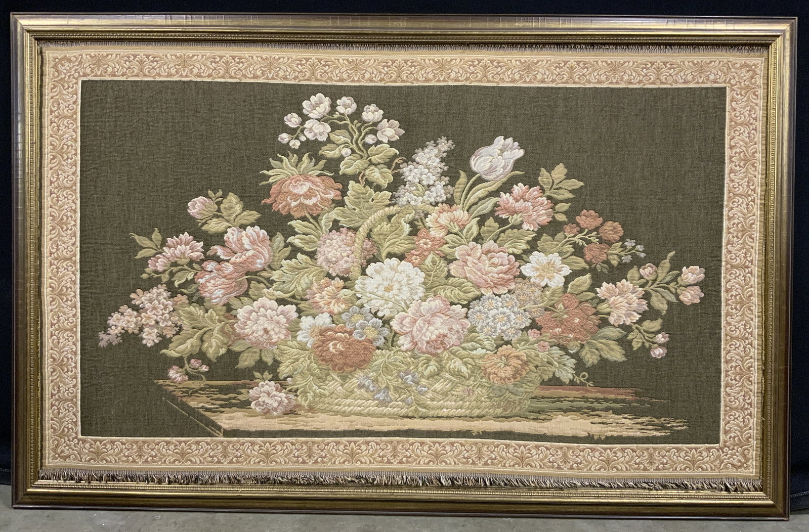 Framed Flower Basket Loom Woven Tapestry 48in: Loom Woven Tapestry. Subject depicts a still life of a basket filled with lush Wild flowers in muted pinks, blues, reds and purples. Tapestry border has scrolling acanthus leaf motifs. Frames in a gil