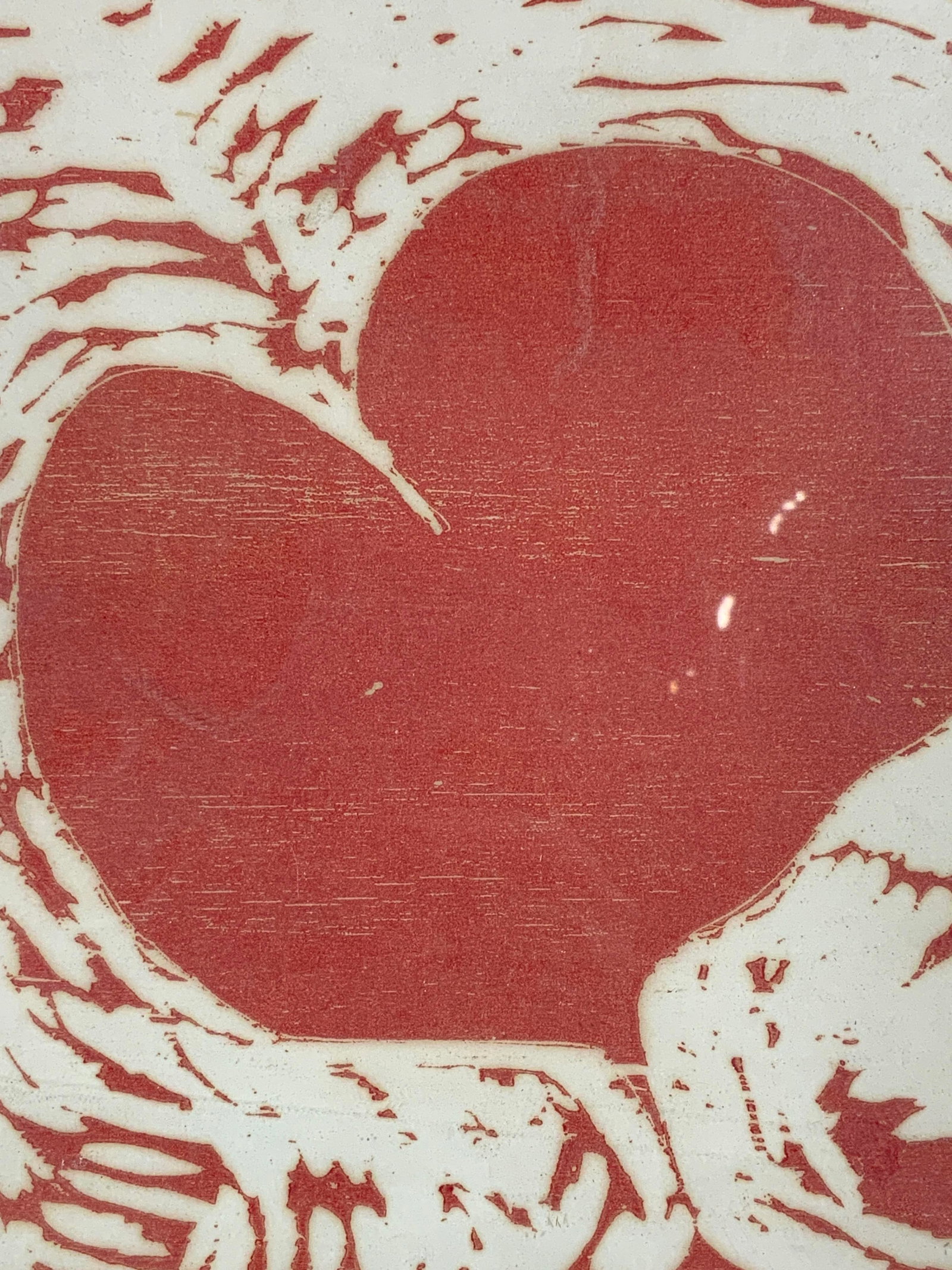 Framed Feathery Red Heart Wood Cut: Woodcut print. Subject depicts a heart with feather style cuts surrounding the heart. Framed in a white toned metal frame. Frame measures approx. 9 W x 11.5 H in. Window measures approx. 8.5 W x 11 H 
