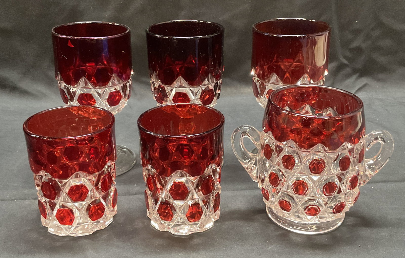 Lot 6 Red to Clear Lowball & Wine Glasses: Lot of 6 ruby red to clear cut lowball, wine, and double handle glasses. Largest glass measures approx. 3 x 6 inches. All pieces have some surface wear including scratching and small chips observed. W