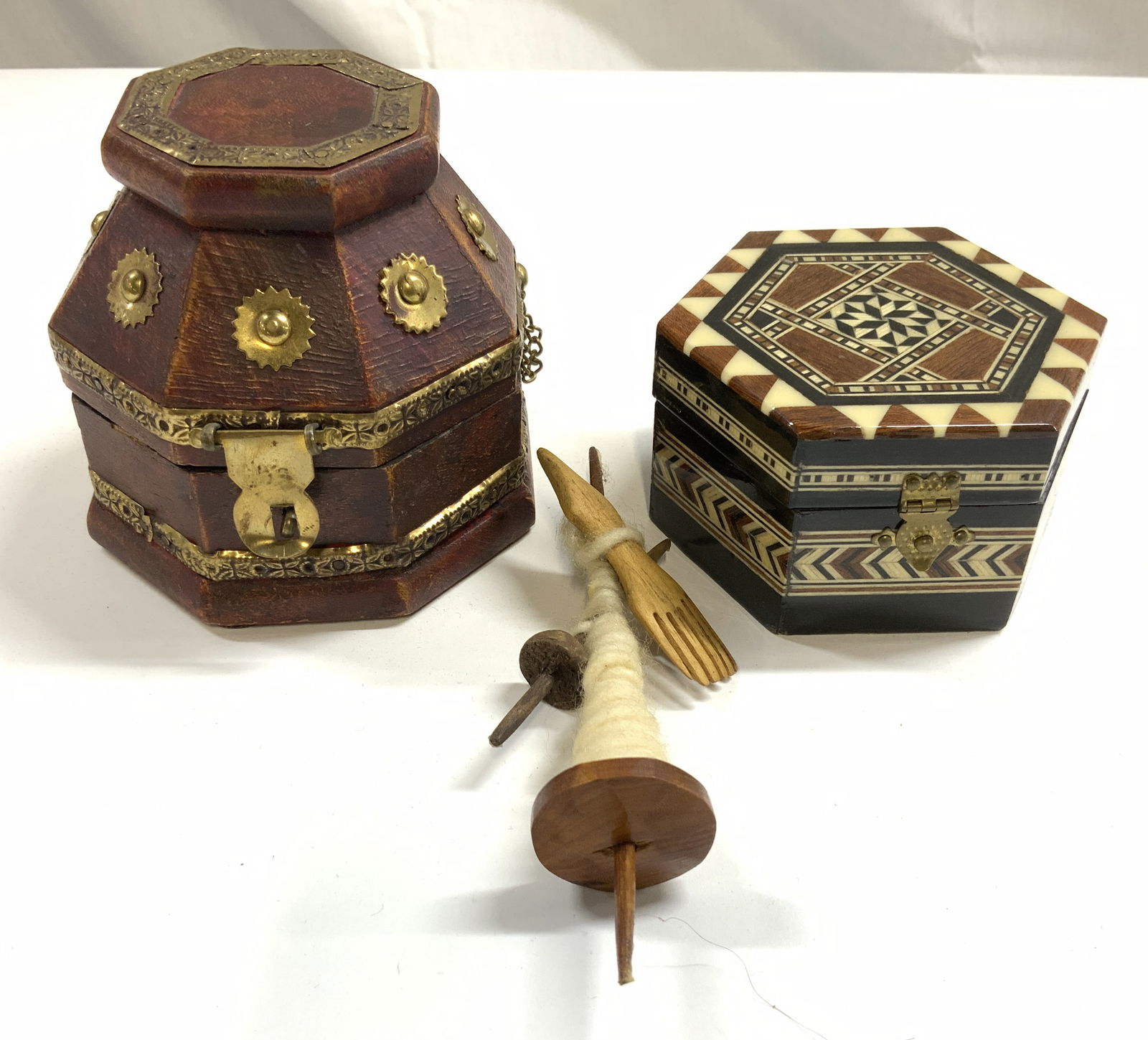Lot 3 Trinket Boxes & More: Lot includes 1 composite trinket box with lid, brown with gold toned gilt metal adornments, 1 bone & wood inlay trinket box wit lid, & yarn spindle. Interiors of boxes are red toned. Largest box measu