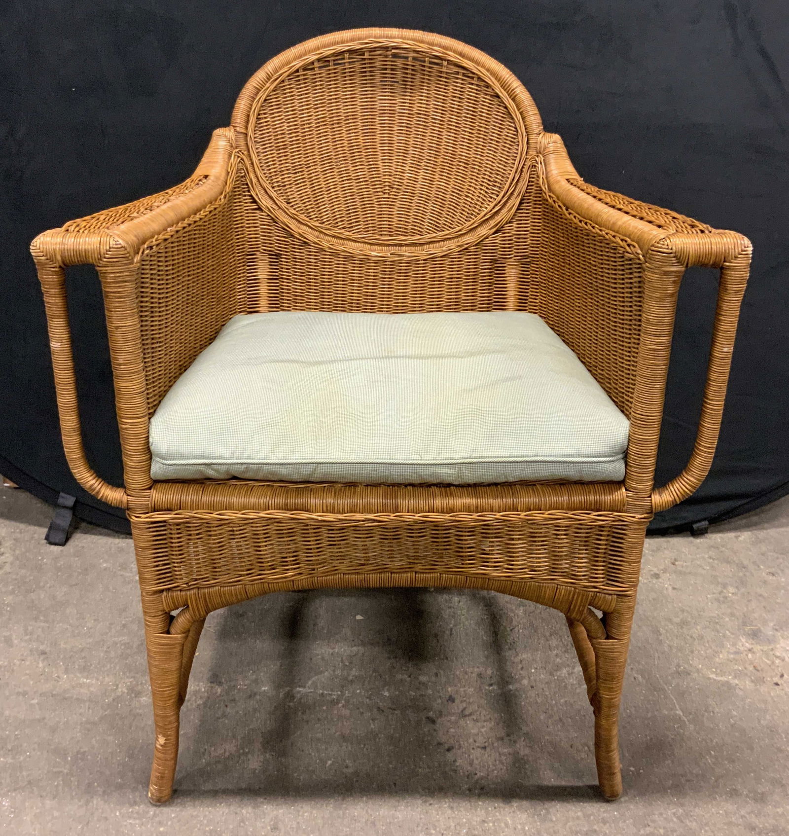 Wicker Armchair W Cushion Tan: Armchair is tan toned. Piece is crafted with woven wicker. Chair includes light green toned cushion. Chair Measures approximately 35.5 inches tall 28.5 inches wide 25 inches deep. Chair, armchair, wic
