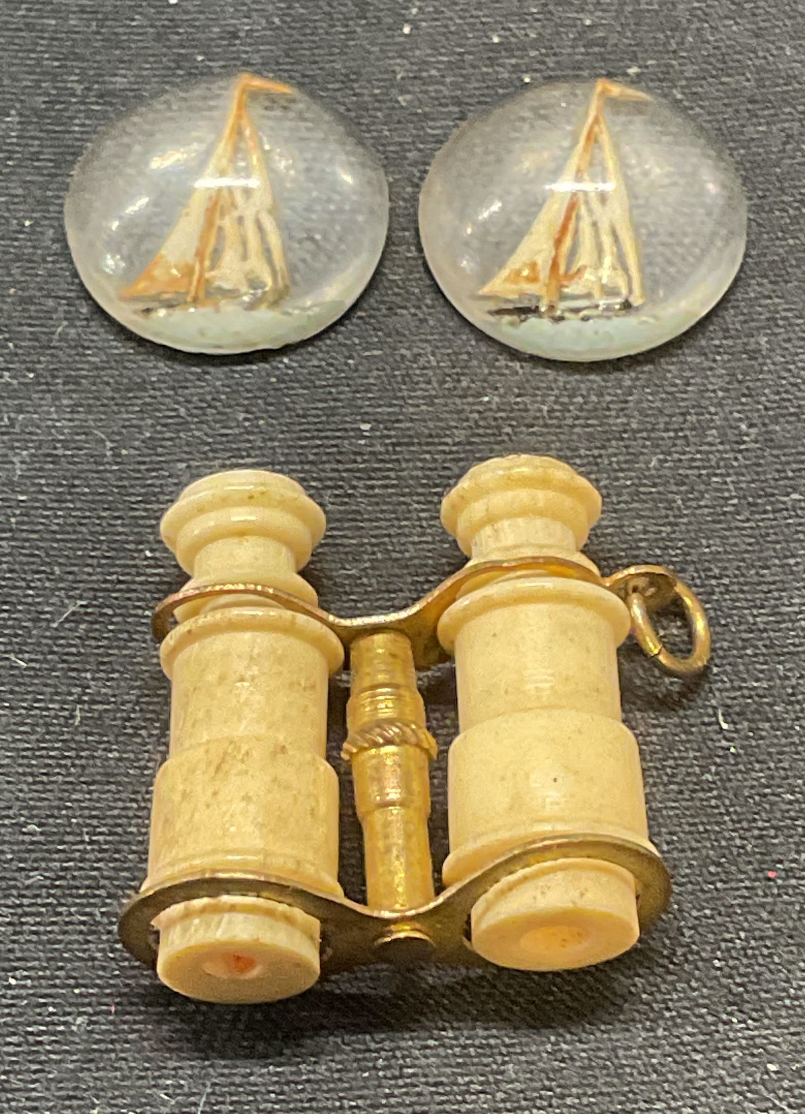 Lot 3 Ship Motif Accessories & Binocular Pendant: 2 composite ship motif craft accessories and bone and gold tone binoculars motif pendant. Largest piece measures approx. .75 x .75 inches. All pieces have some surface wear including scratching observ