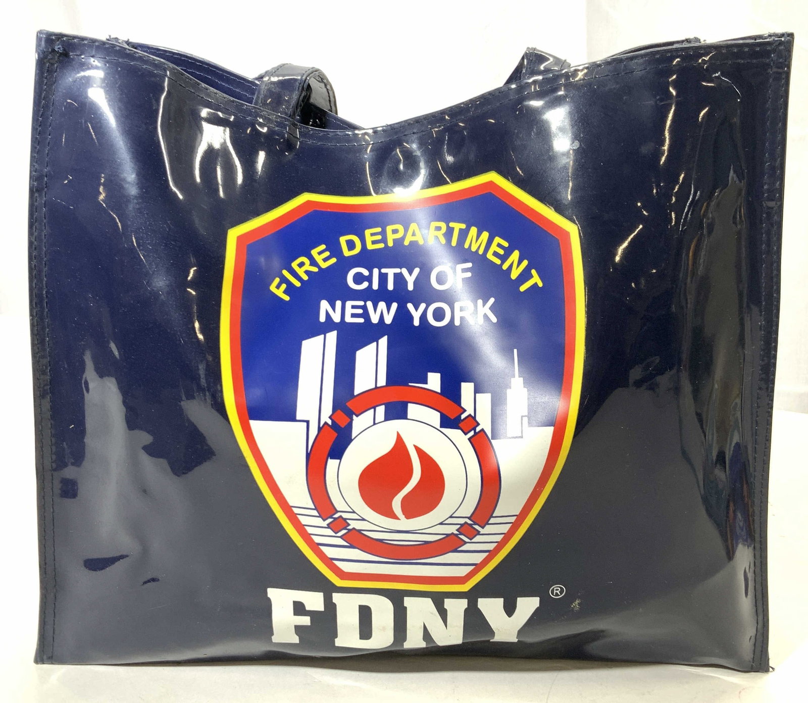 FDNY Vinyl Tote Bag, NWT: City of New York Fire Department vinyl tote bag. New old stock. With original tag attached. Has the World Trade Center and former city skyline with FDNY on both sides. 13.5 in. L x 11.25 in. x 4.5 in.