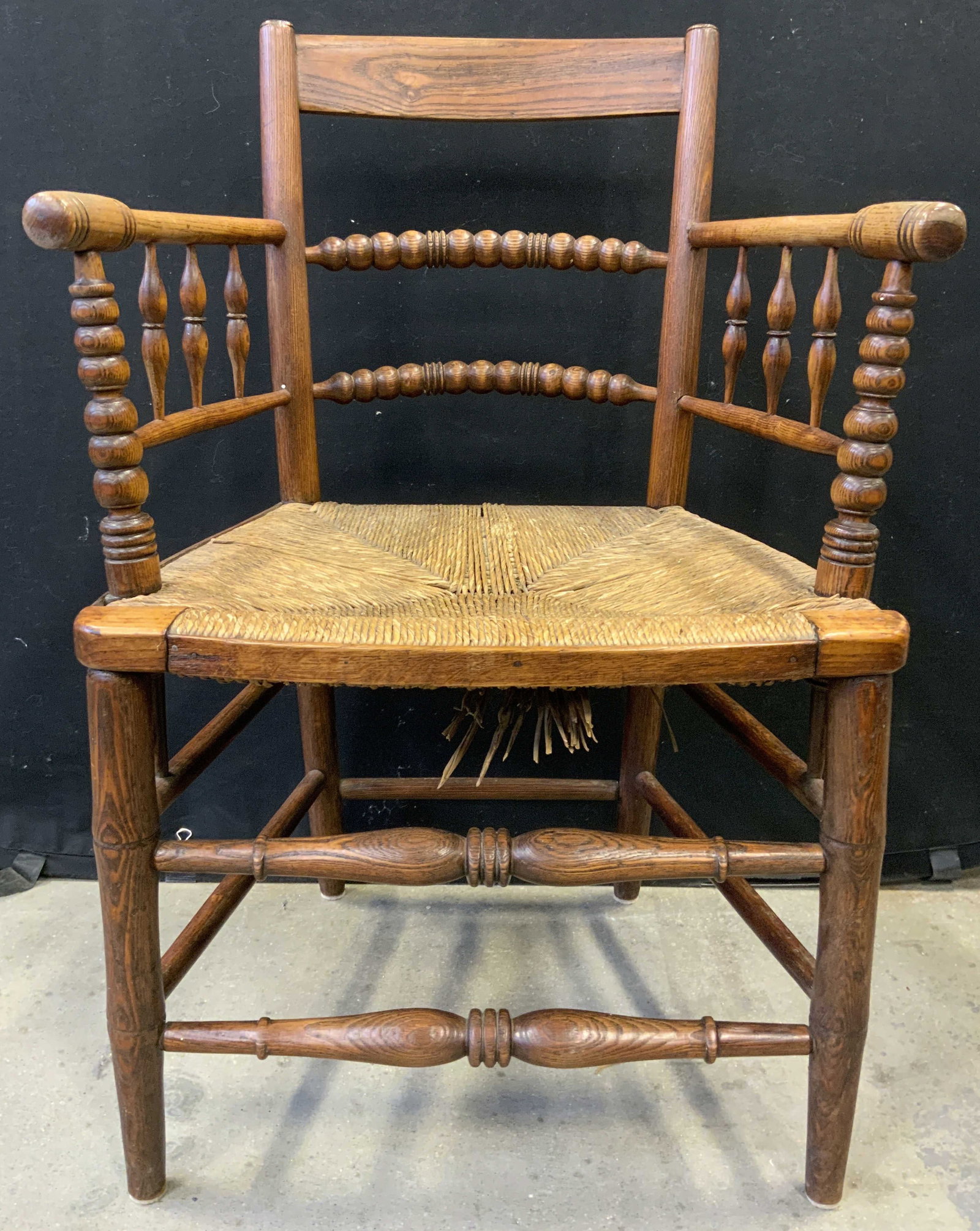 Antq Carved Wooden Bobbin Chair W Rush Seat: Chair is antique and wooden. Piece has Rush seat. Vintage bobbin chair with carved wooden detail. Chair has 4 legs with box stretcher in between. Measures approximately 33 inches tall 22 inches wide 1