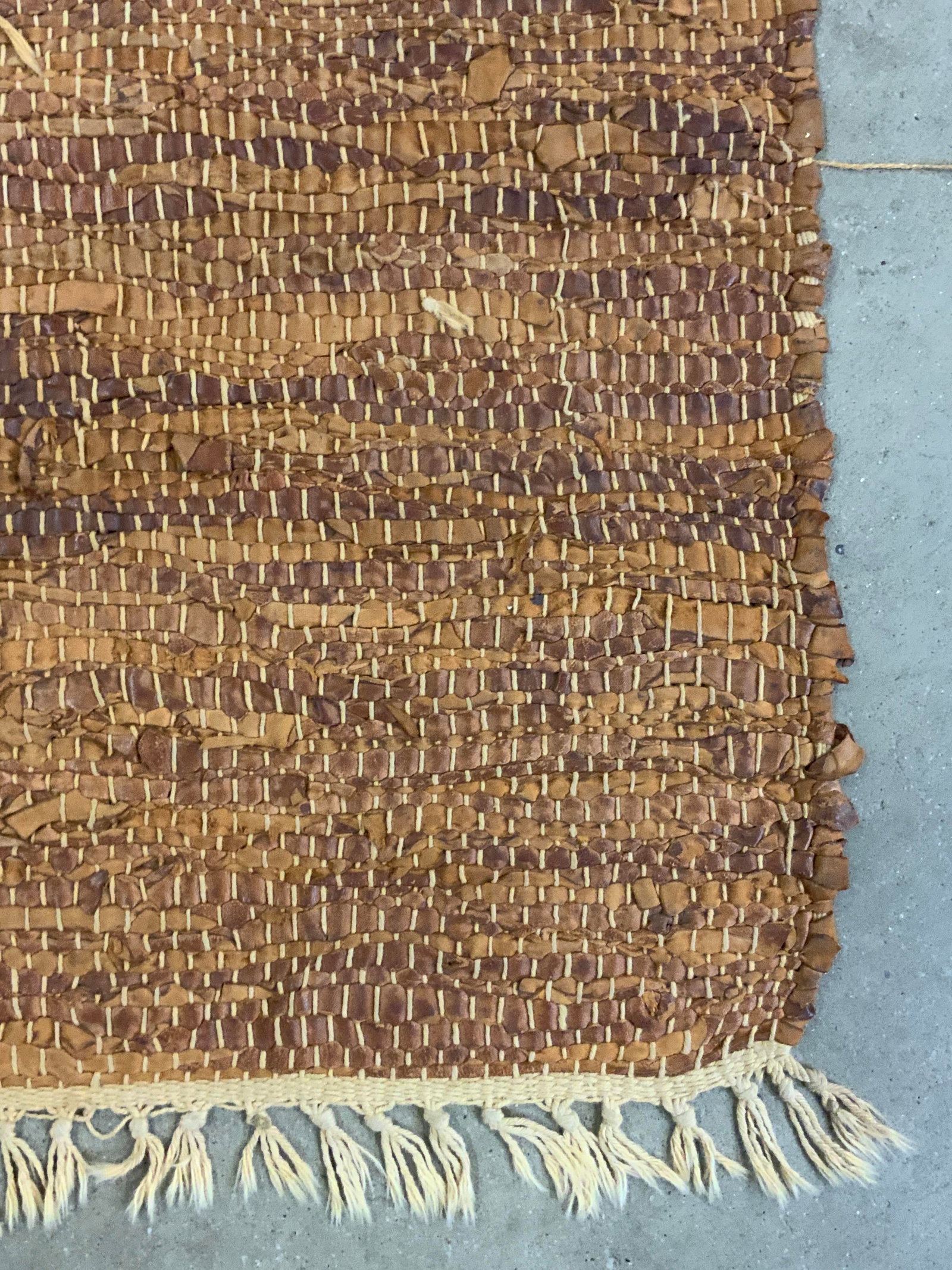 Vintage Woven Leather Fringe Trim Rug: A vintage woven leather fringe trim rug. Light brown hues. Measures approx. 76L x 41W in. Measurement includes fringe. Some losses to the leather and surface wear present. Home decor, home accents, ho