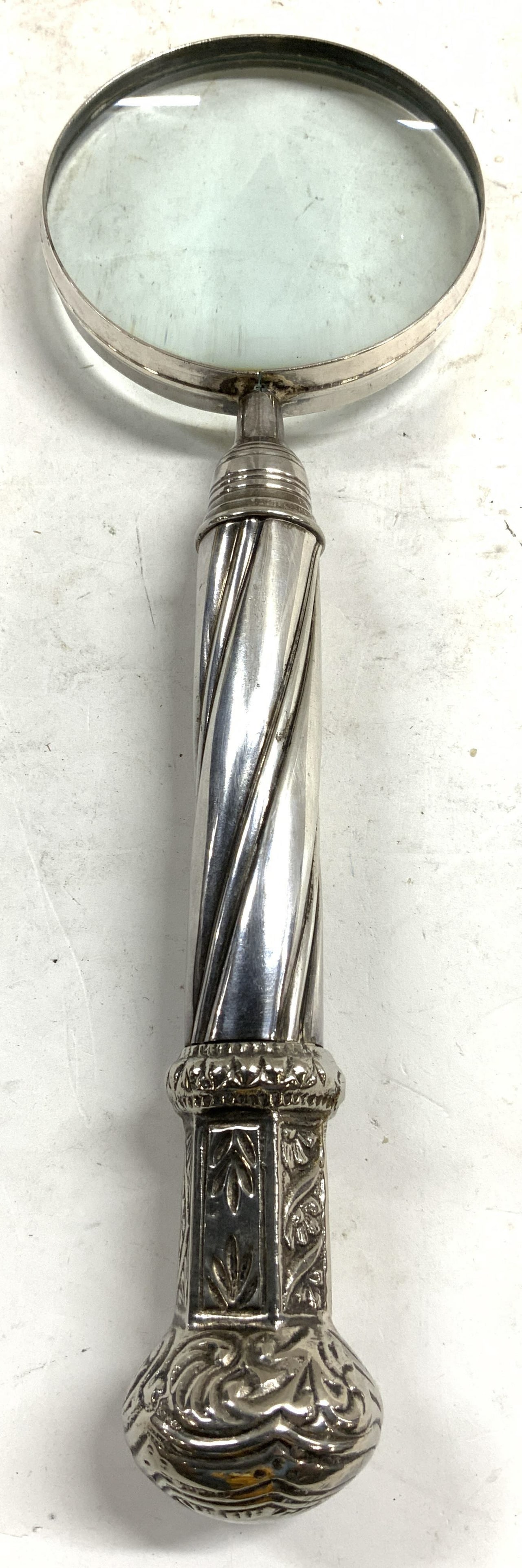 Vntg Pewter Handle Magnifying Glass 12in W Case: Magnifying glass is silver toned, handle appears to be pewter. Piece has relief detail at end & twisted structure to center of handle. Lot also includes black toned crushed velvet carrying case. Magni