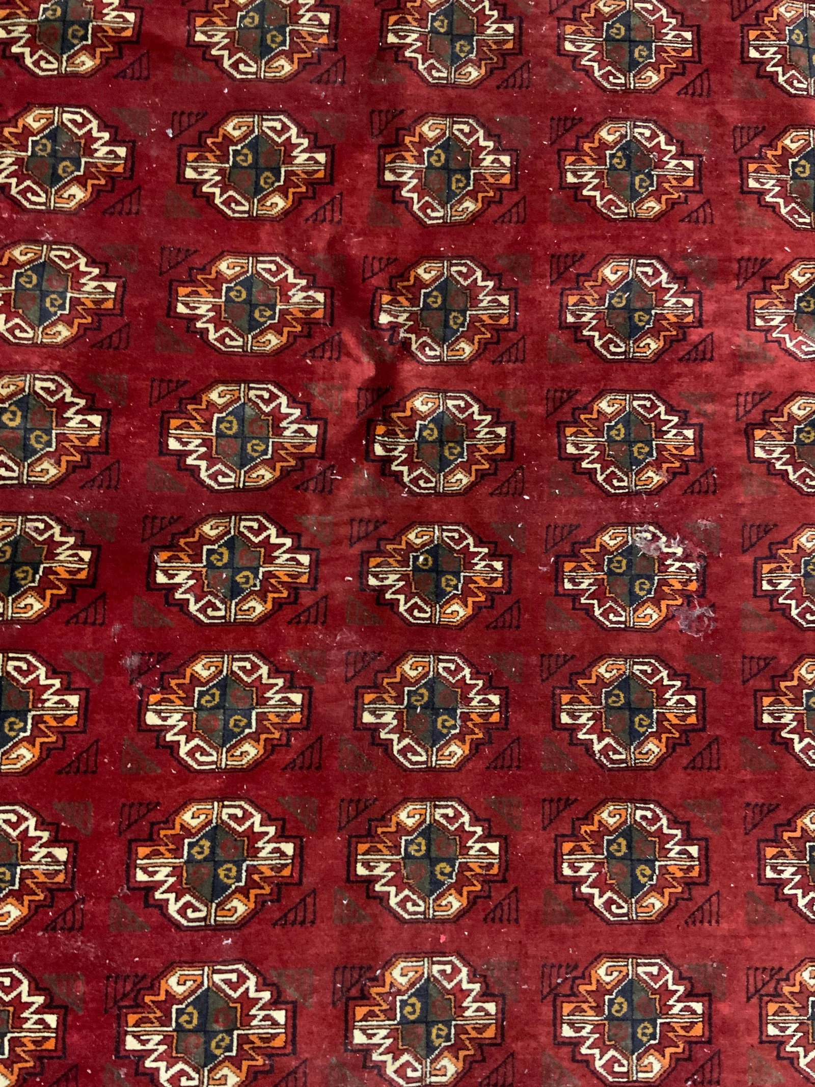 Vintage Handmade Persian Bokhara Fringe Trim Rug: A vintage handmade Persian Bokhara rig with fringe trim. Multicolored medallions to the center alongside geometric patterns. Measures approx. 115L x 81W in. Measurement includes fringe. Some discolora
