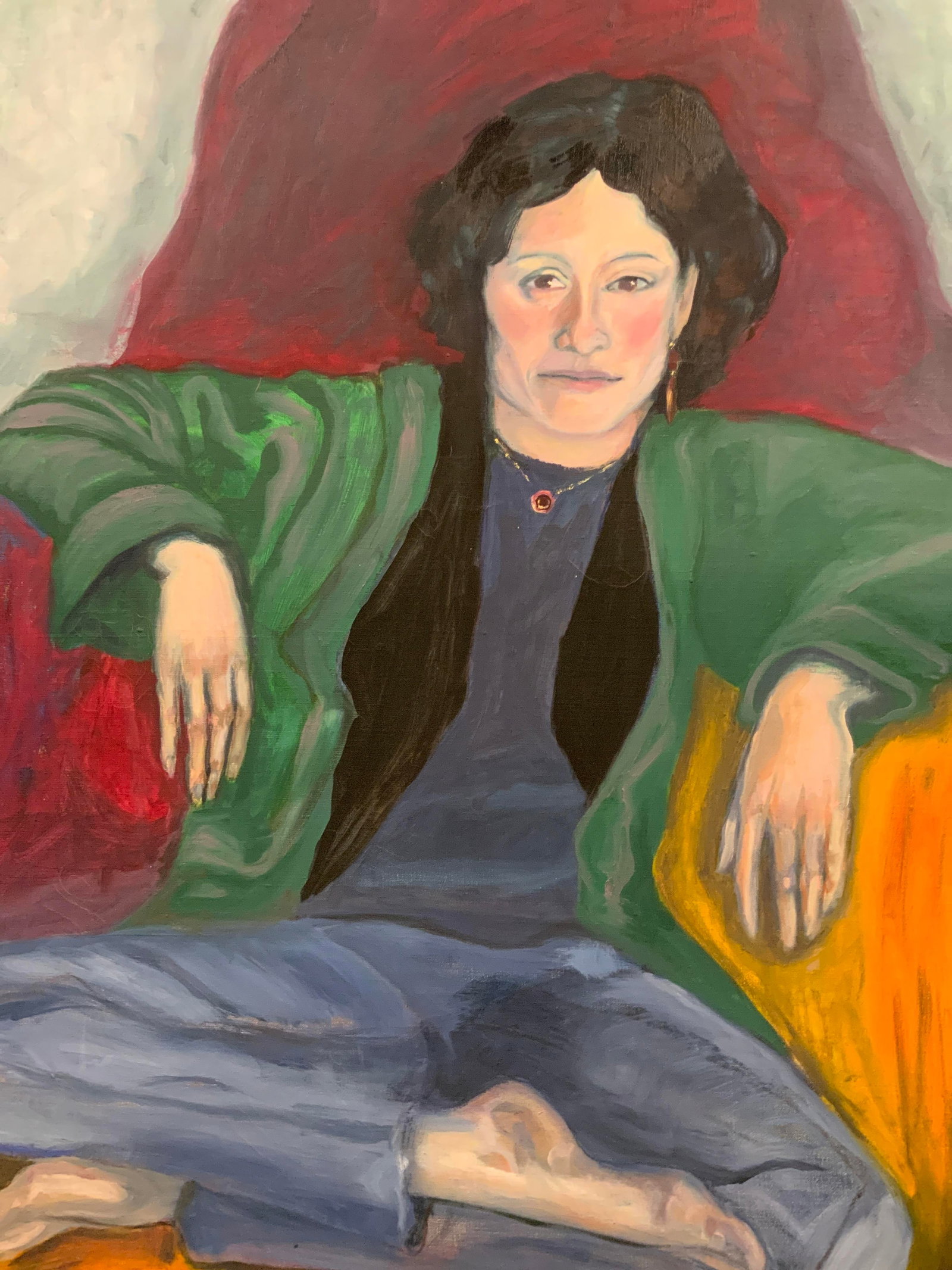 Framed Woman Sitting Portrait Large Oil Painting: Oil paint on canvas. Subject depicts a woman sitting and posing for her portrait in jeans, a green cardigan and a purple necklace. Framed in a dark brown wooden frame with black carved motif accents. 