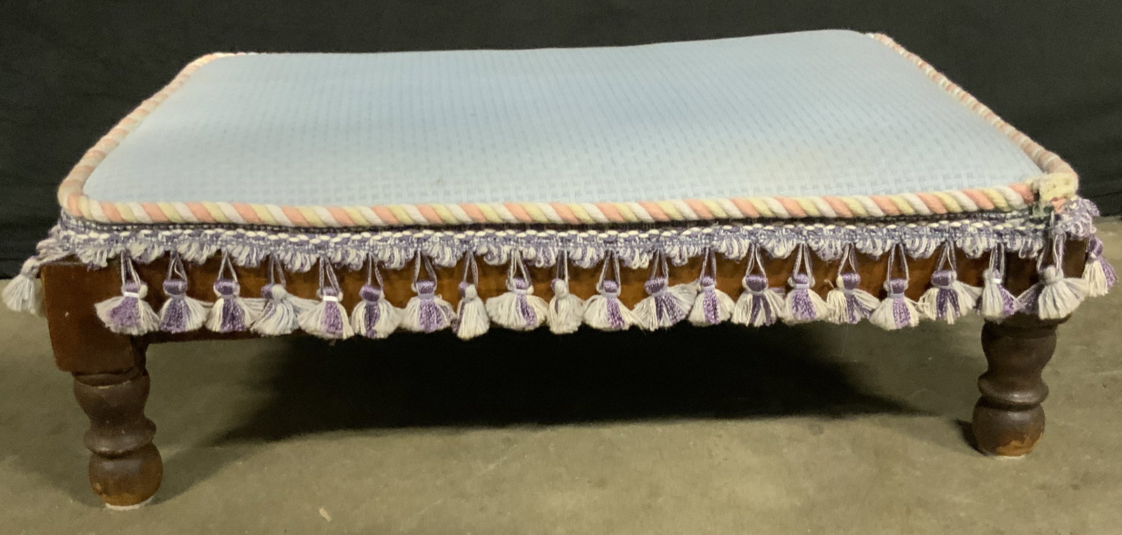 Vntg Rectangular Upholstered Tassel Trim Footrest: A vintage blue hued tassel trim footrest. Rectangular form. Soft hand upholstery. Measures approx. 7H x 13.5D x 20W in. Some discoloration, chipping, and surface wear present. Vintage Rectangular Upho
