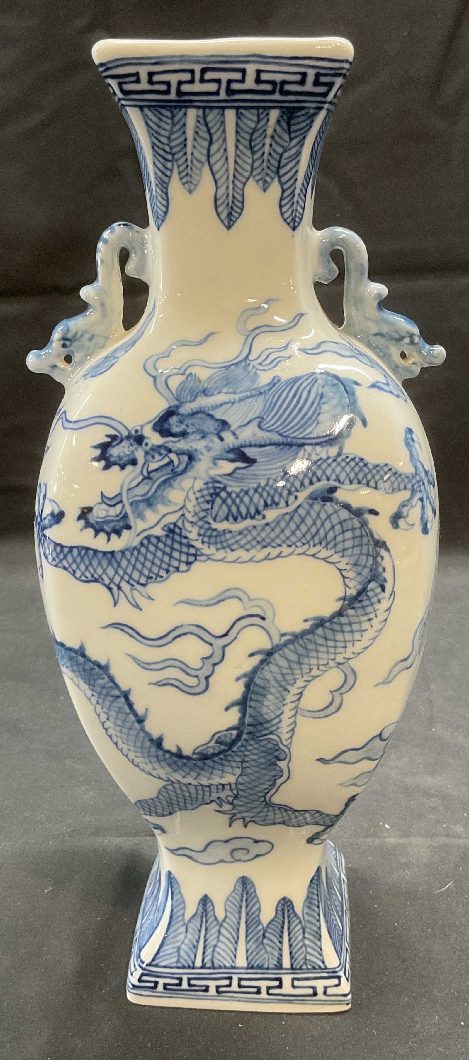 Signed Chinese Porcelain Dragon Vase: Signed Chinese porcelain vase. Blue and white. Hand painted. Dragon finial detail. Piece has weight. Signed to underside. Measures approx. 4 x 4 x 10.5 inches. Some surface wear consistent with exposu